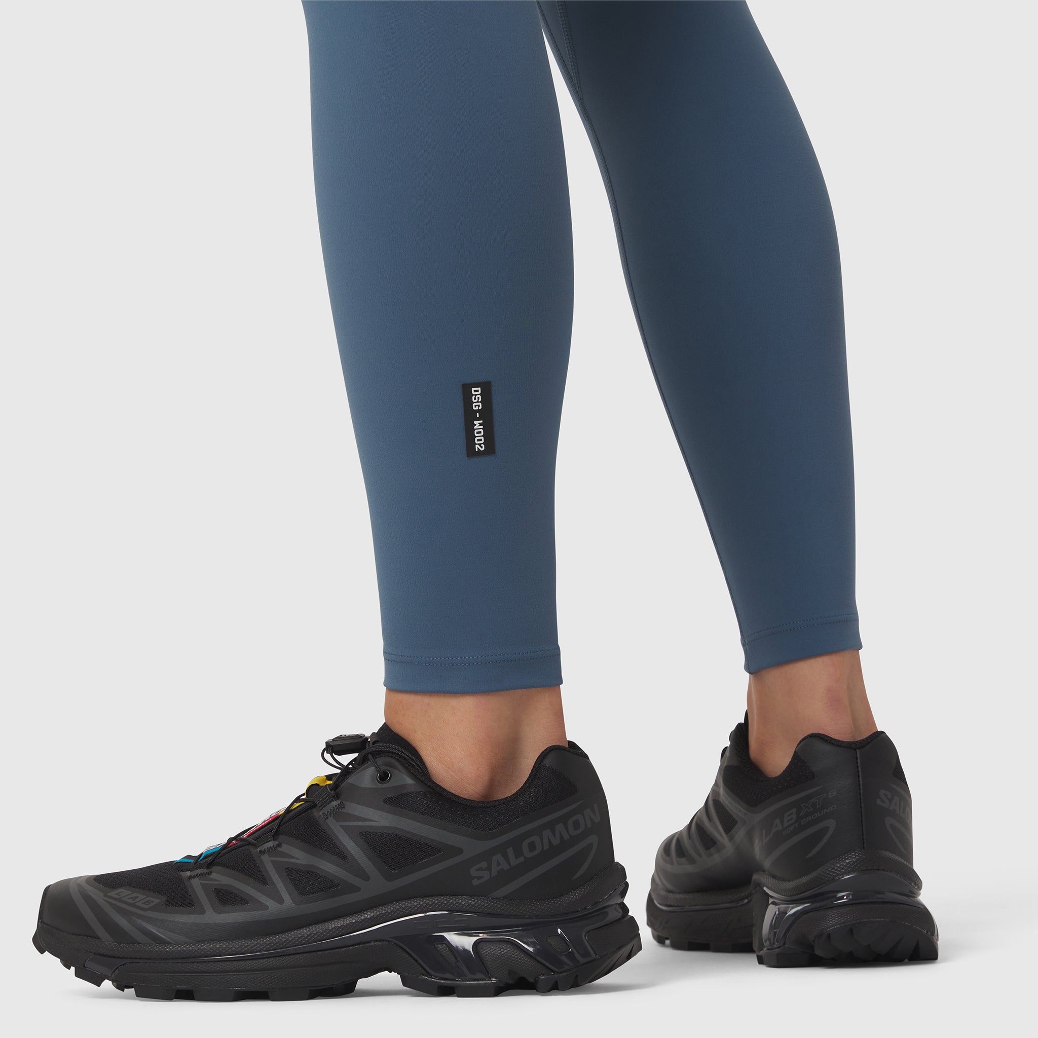 W002 LYCRA® ADAPTIV Legging in storm blue, worn with black running shoes, side view