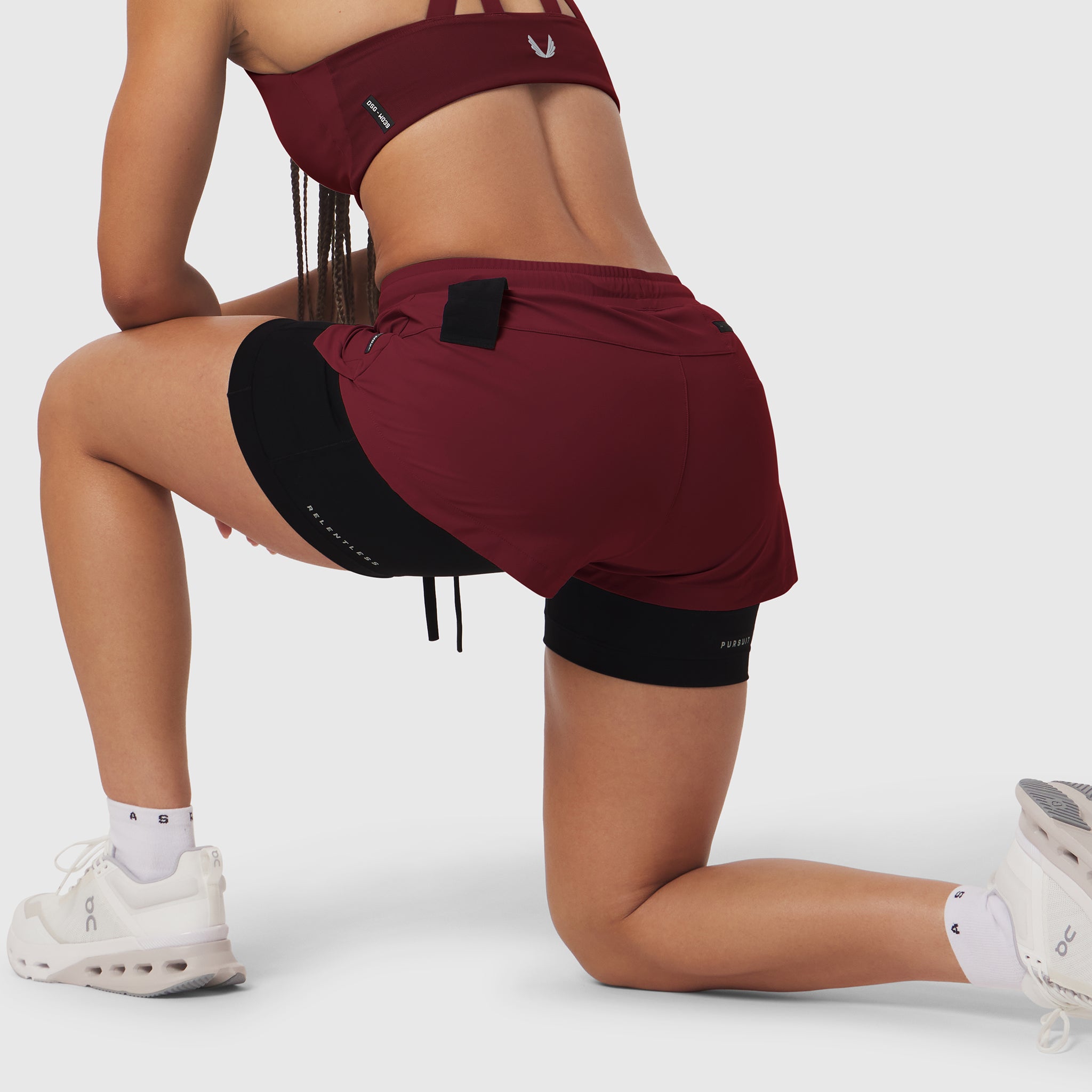 W025 Tetra-Lite Liner Short in crimson with black shorts, worn by model in kneeling pose