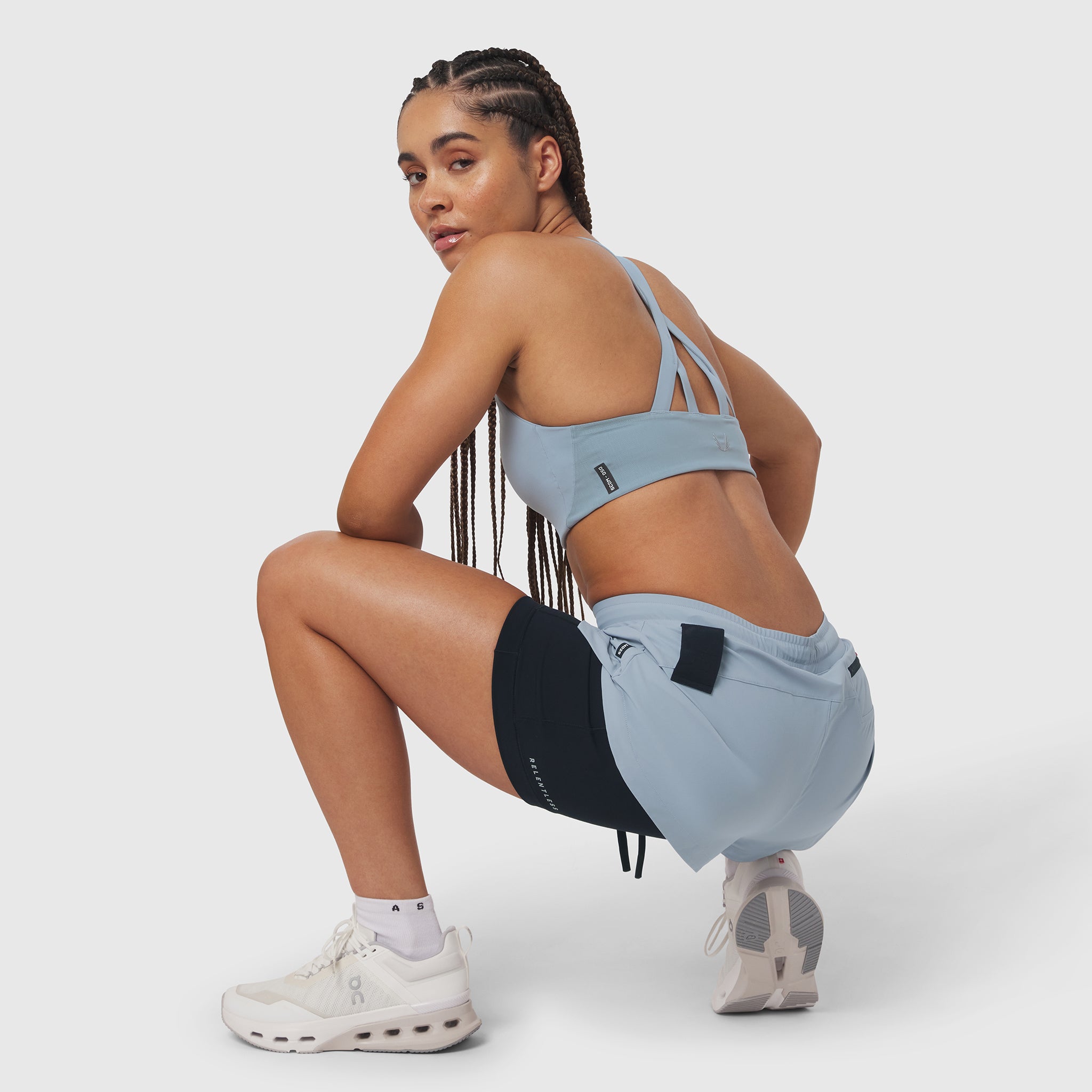 W025 Tetra-Lite Liner Short in Light Sky and black, worn by model in crouching pose