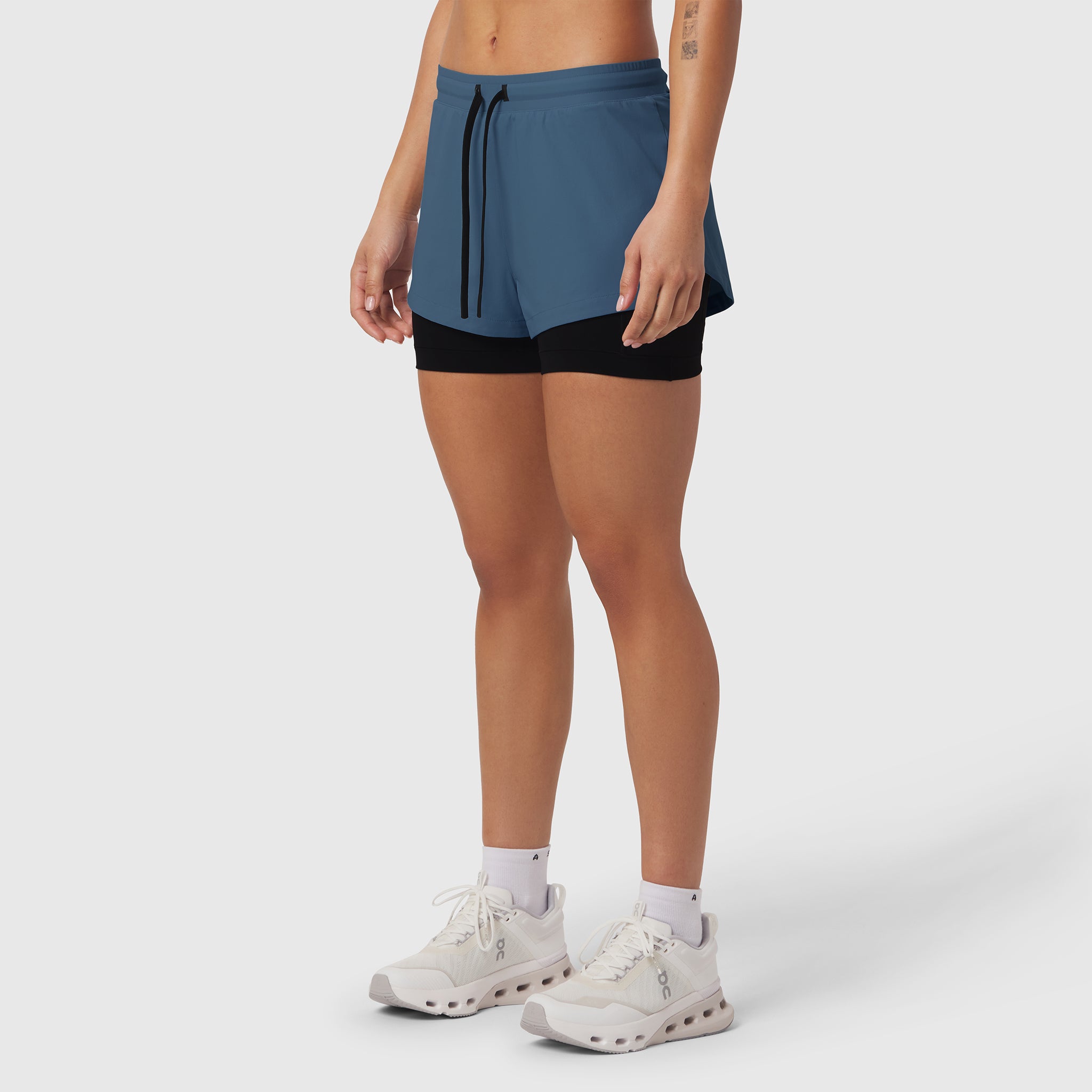 Tetra-Lite Liner Short in storm blue and black, worn by model with white sneakers