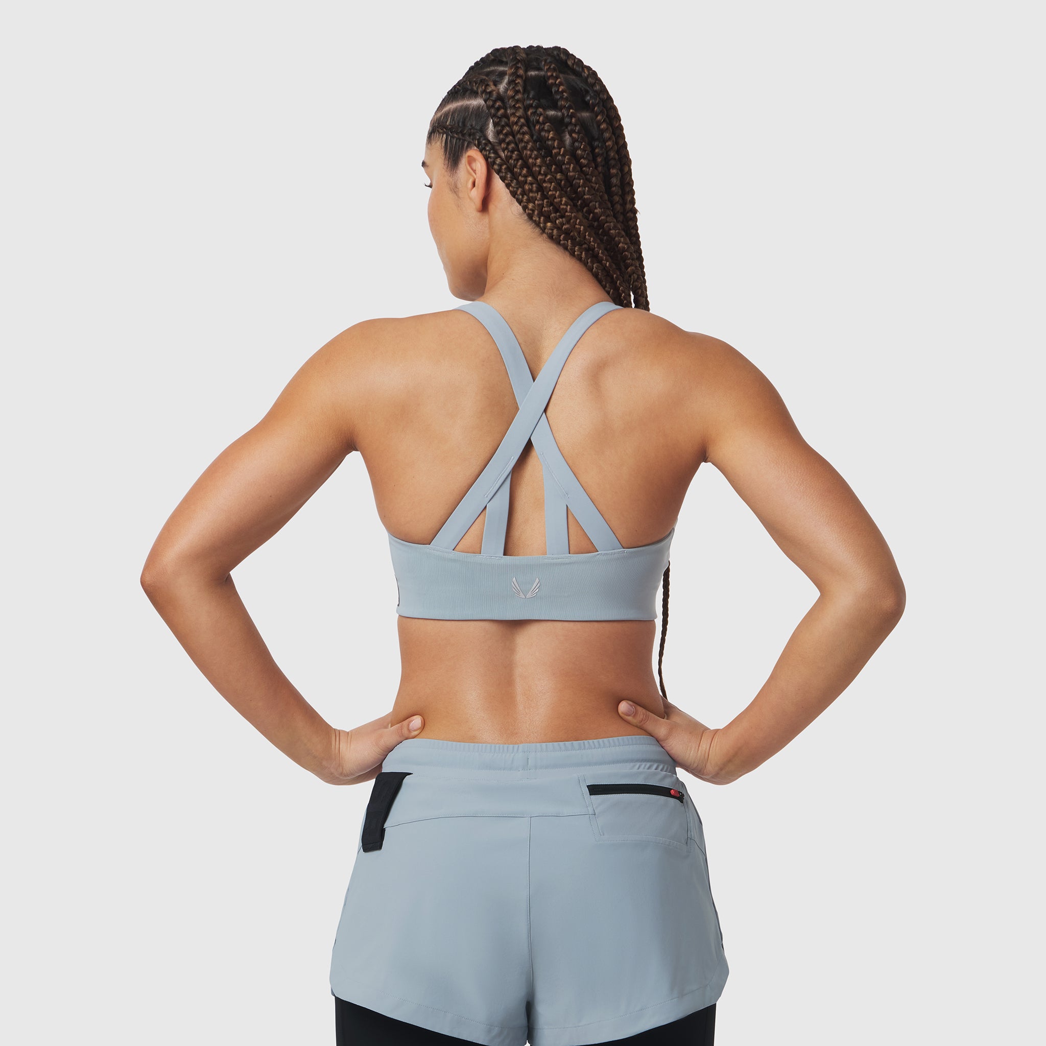 Light sky LYCRA® hybrid sports bra with cross-back straps, worn by model from behind