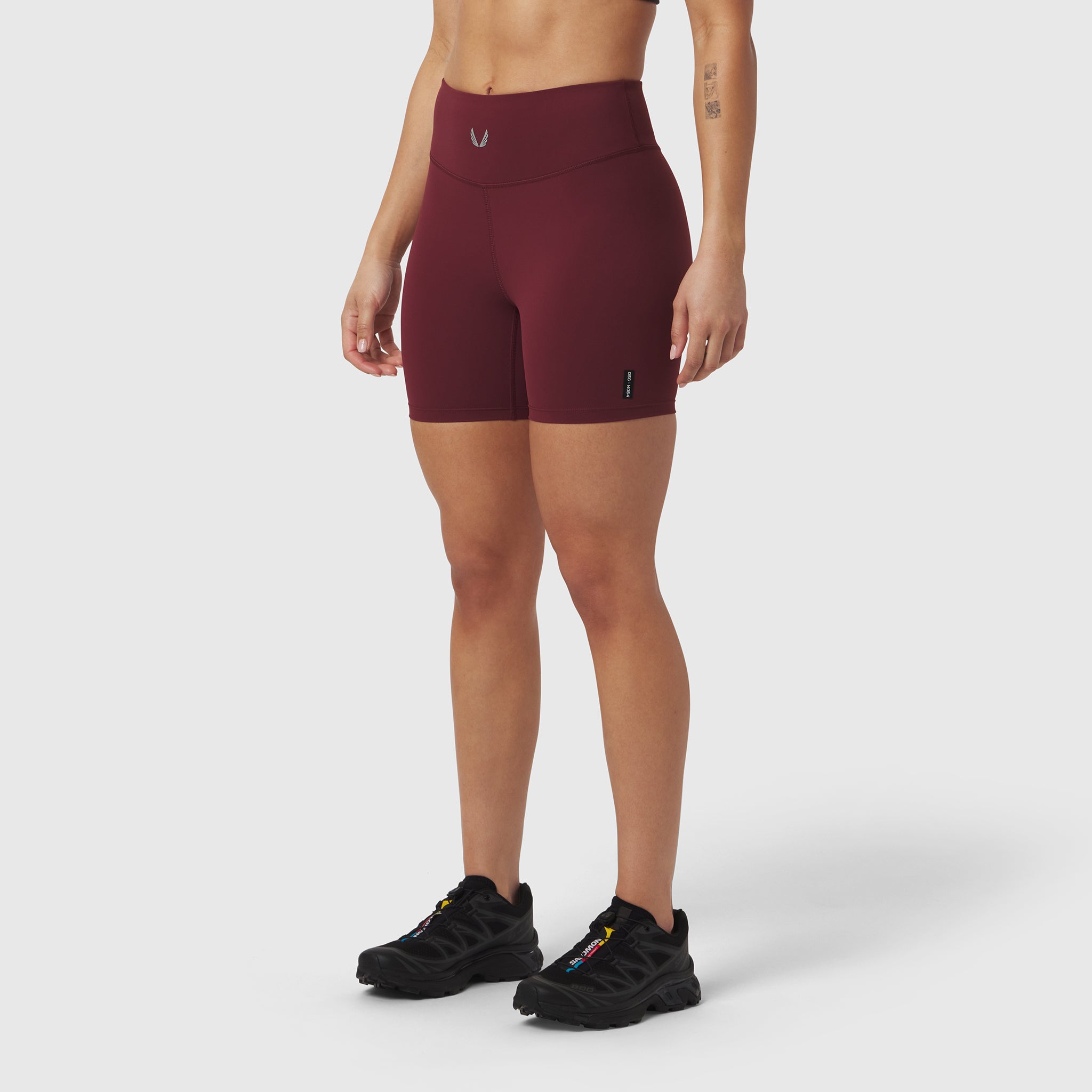 LYCRA® ADAPTIV Biker Short in crimson, worn with black sneakers, front view