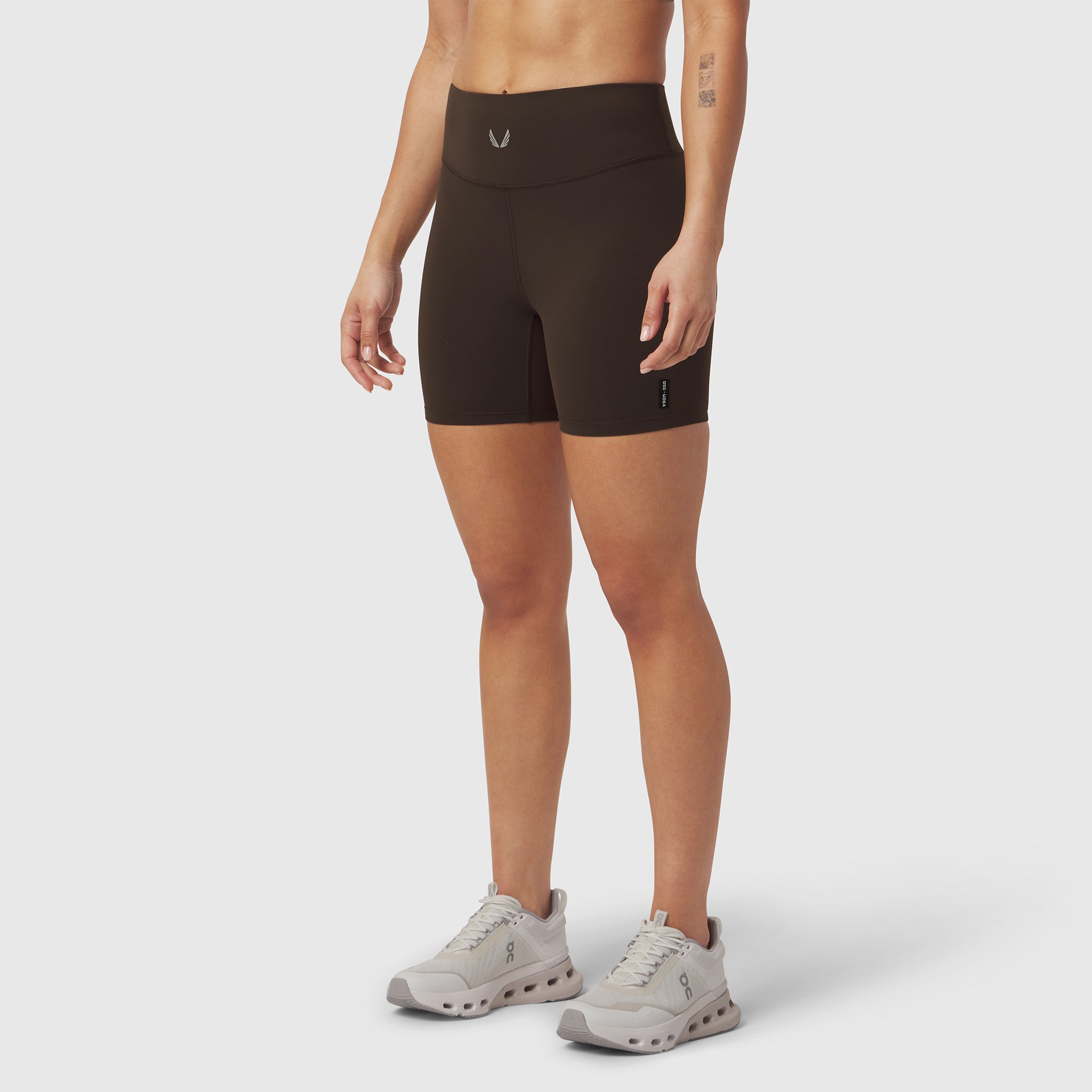 W064 LYCRA® ADAPTIV Biker Short in Dark Earth, worn with white sneakers, front view