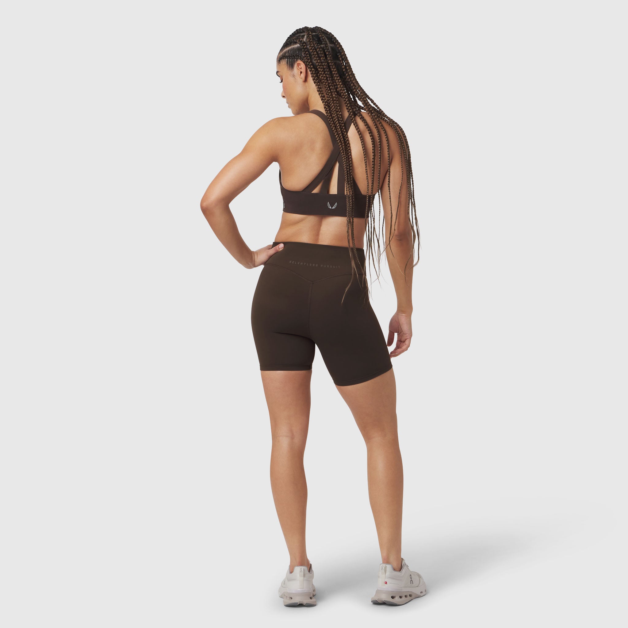 LYCRA® ADAPTIV Biker Short in Dark Earth, model wearing with sports bra, back view