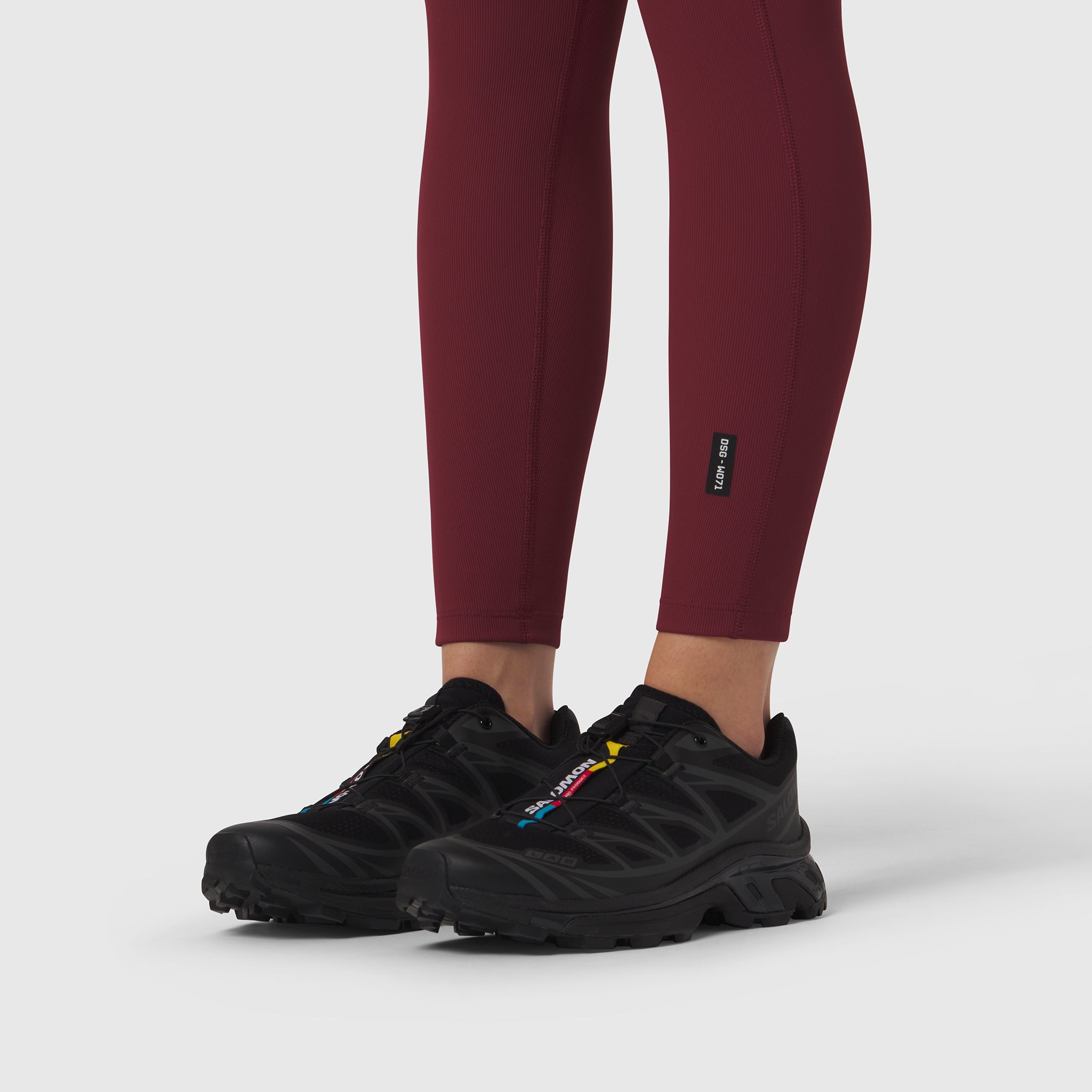 Crimson ribbed leggings worn with black athletic shoes, lower body view