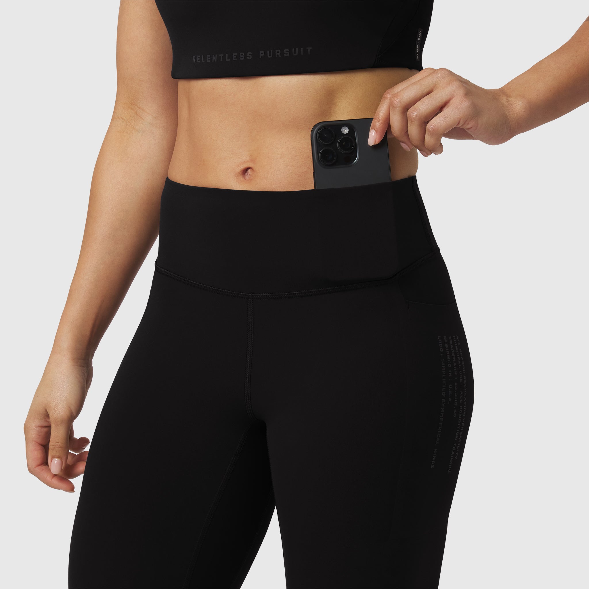 Black LYCRA® ADAPTIV 4 Pocket Legging worn by model, front view with phone in waistband pocket