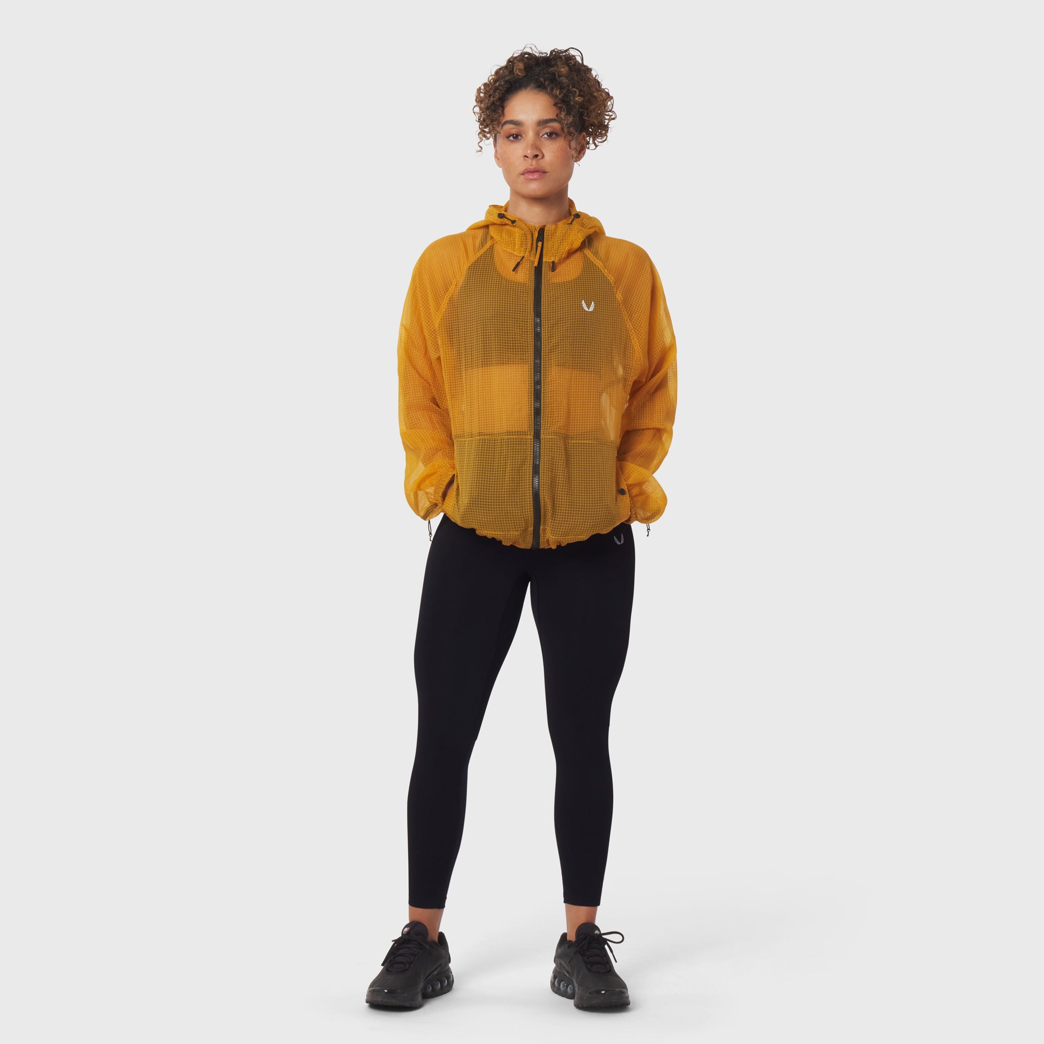Weather-Ready Transparent Ripstop Shell Jacket in amber worn with black leggings, front view