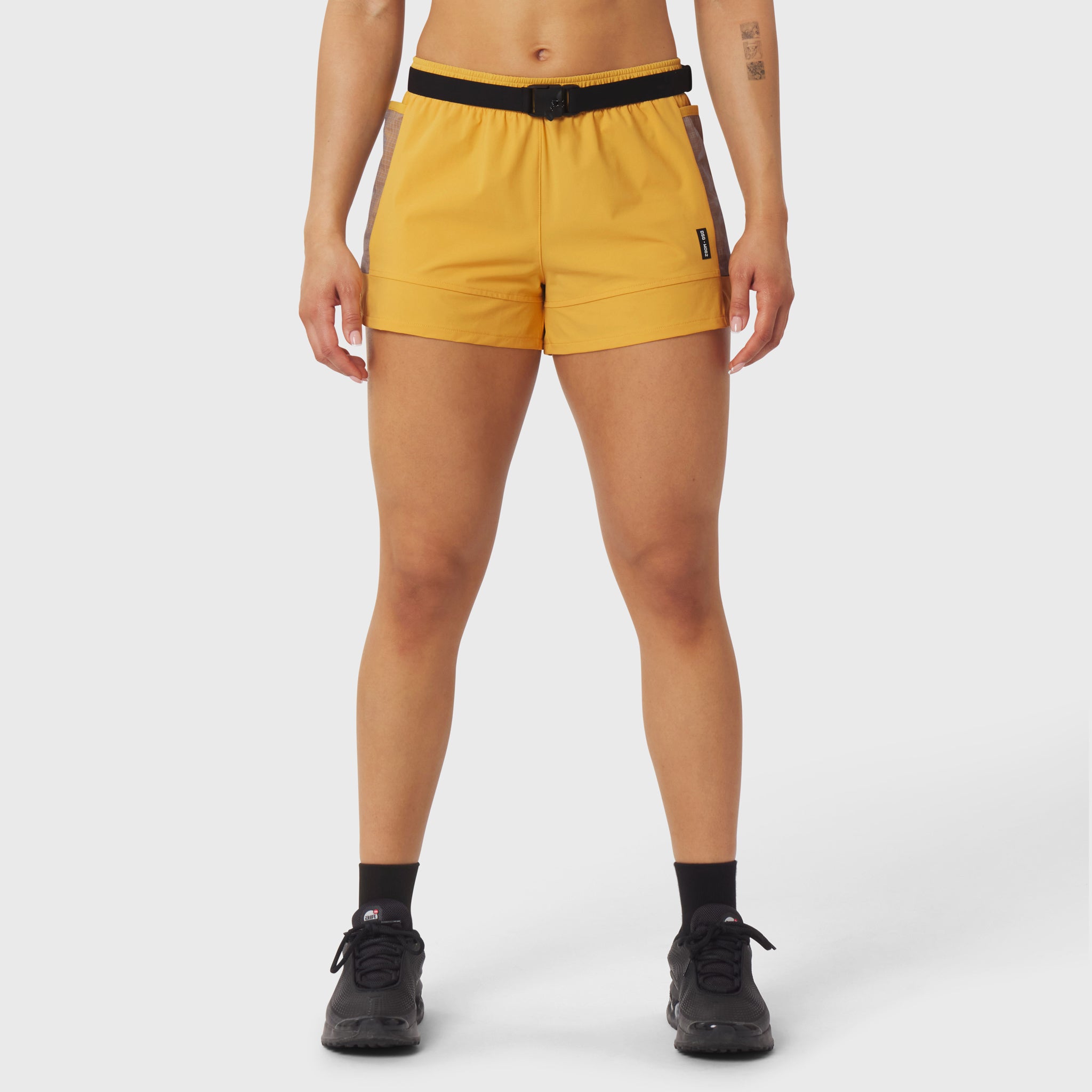 Yellow athletic shorts with black belt on model, front view