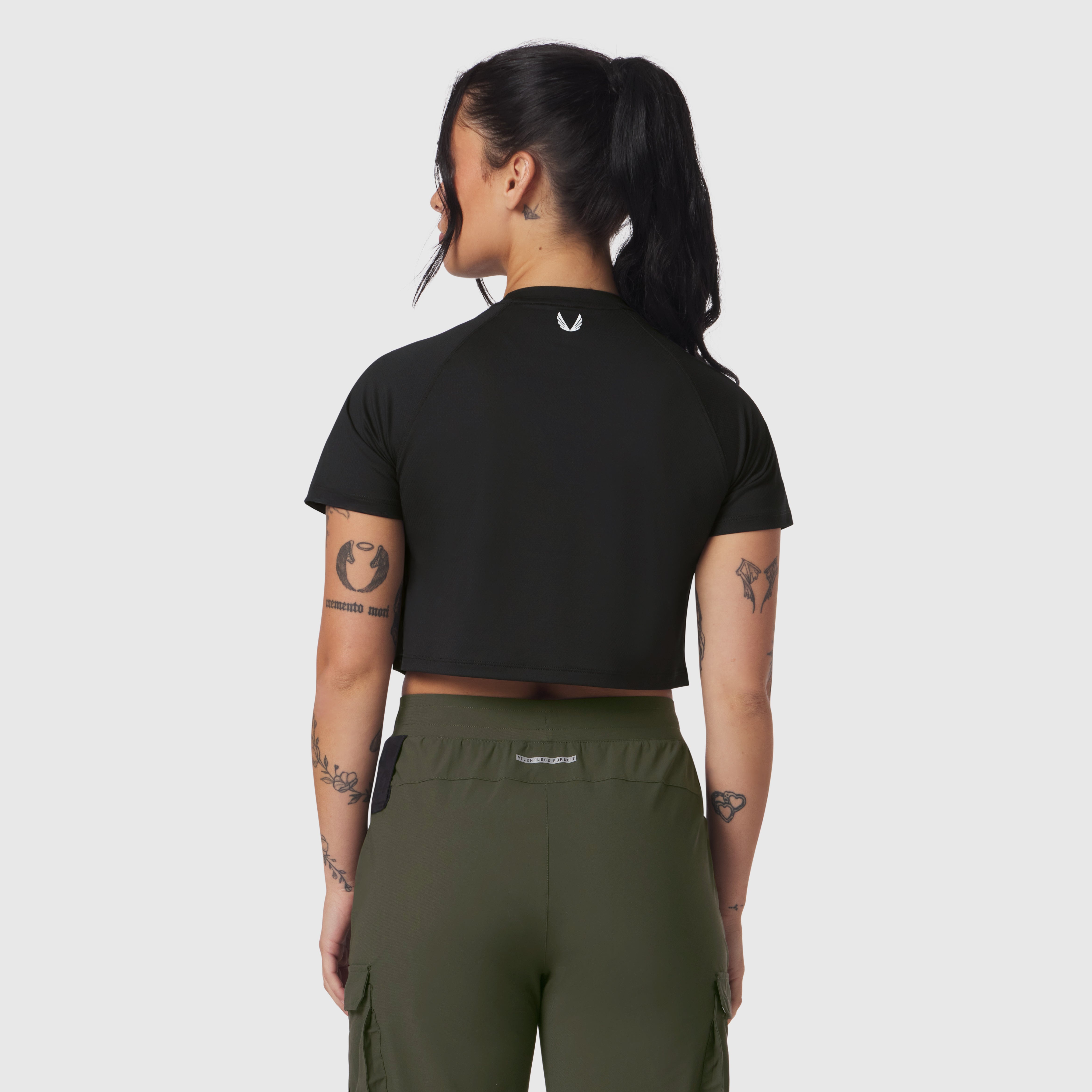 Black AeroSilver cropped tee worn by model, back view, paired with olive cargo pants