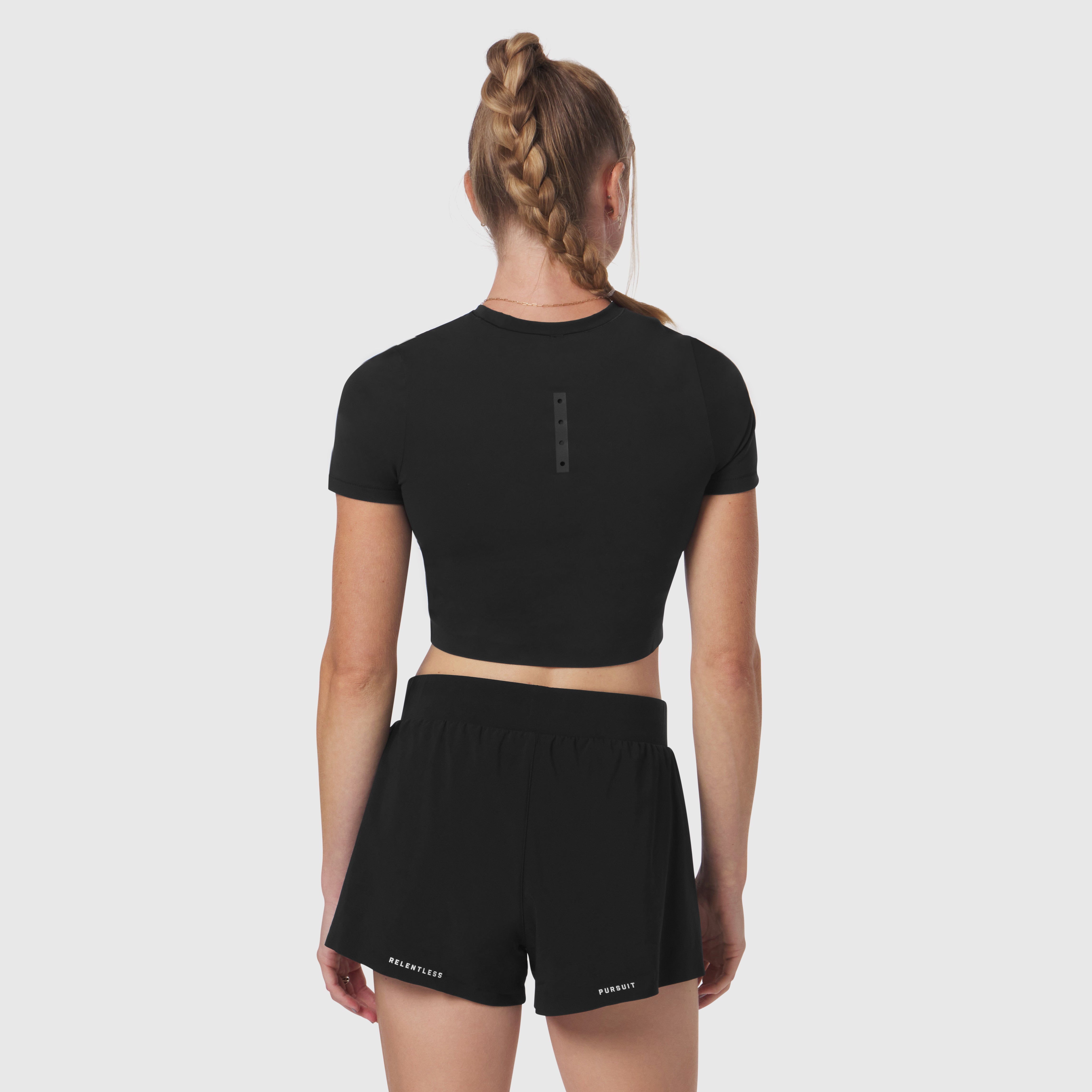 Black LYCRA® cropped tee worn by model, back view, paired with black shorts