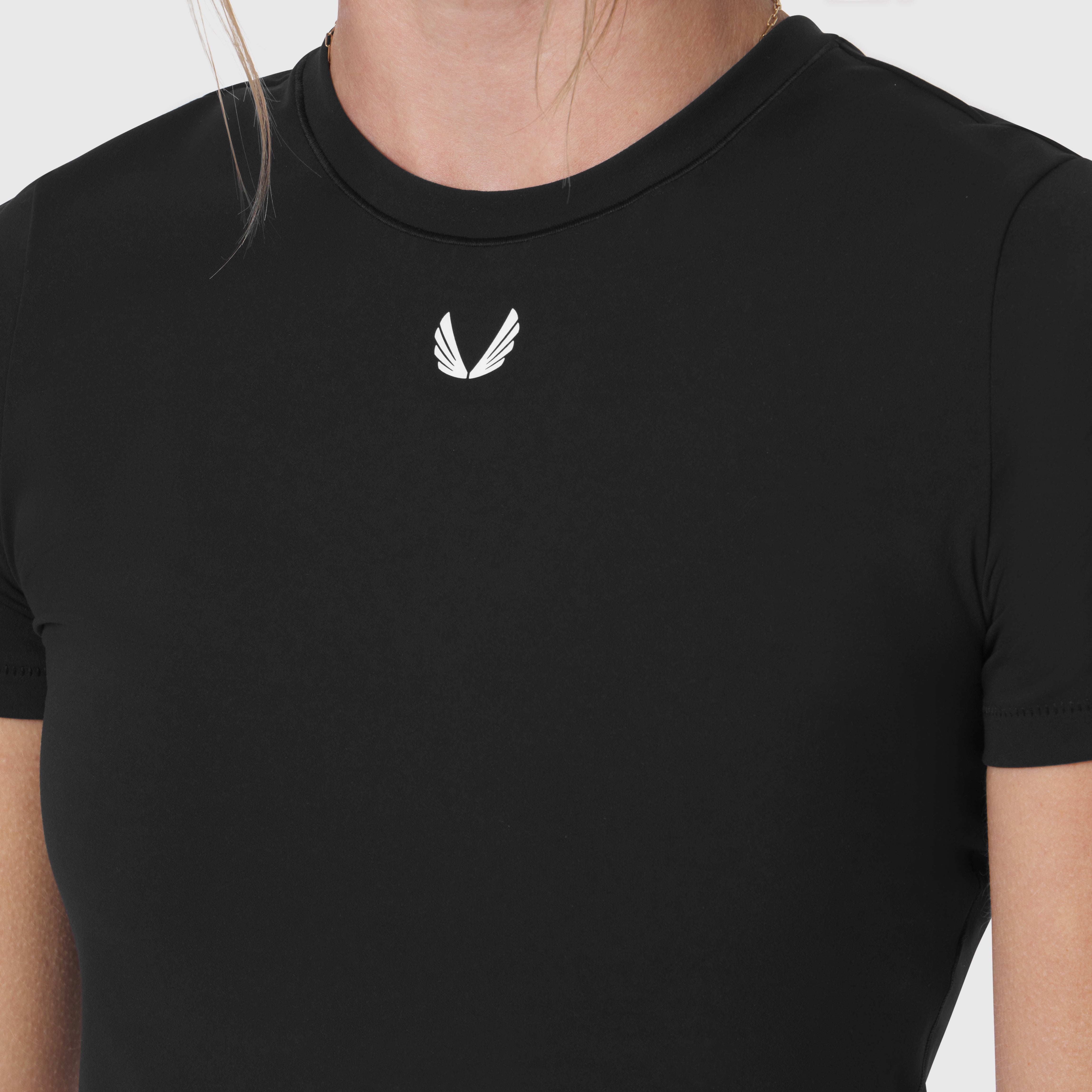 Black LYCRA® cropped tee with small white logo on chest, worn by model