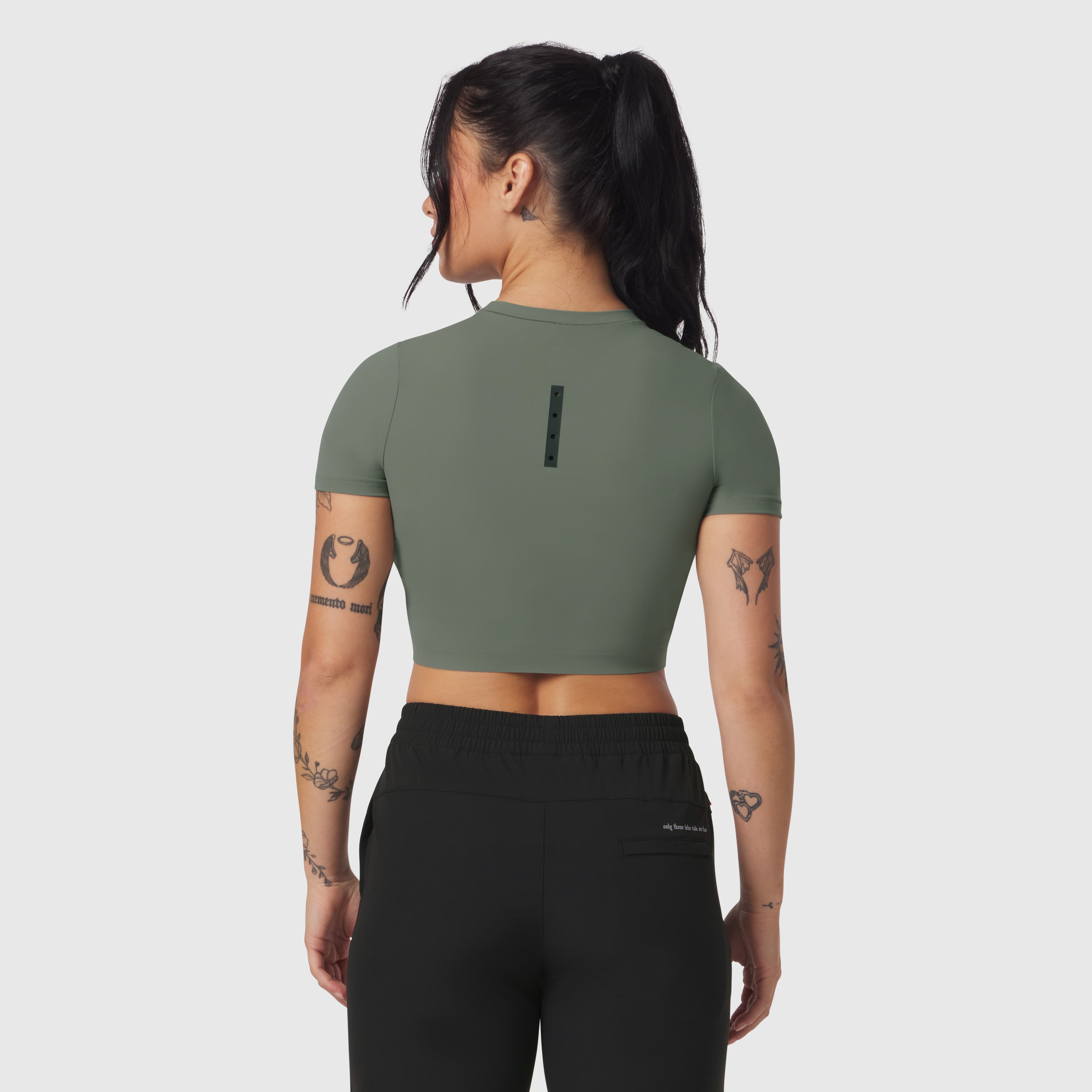 Sage green cropped tee worn by model, back view, with black joggers