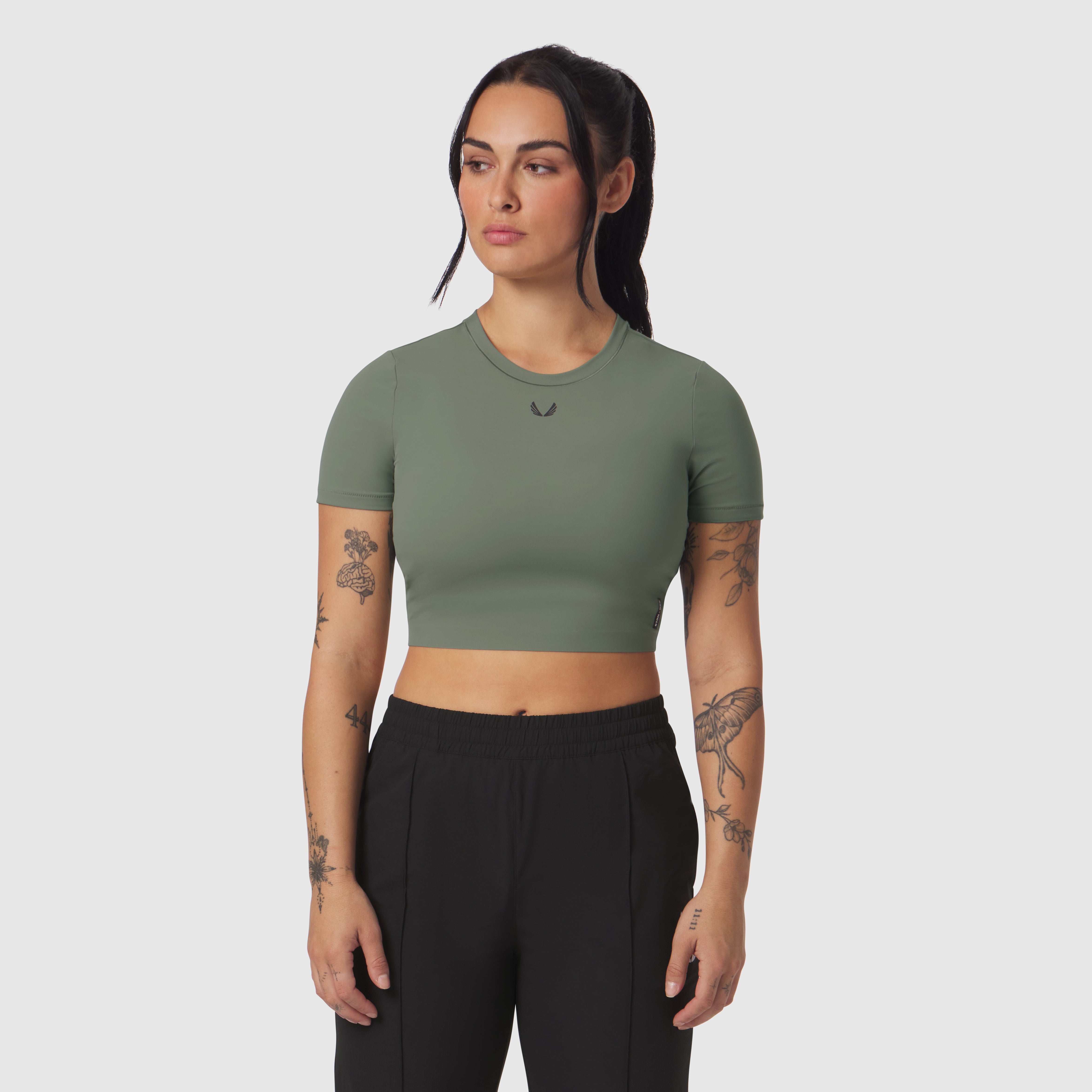 Sage green LYCRA® cropped tee worn with black pants, front view on model
