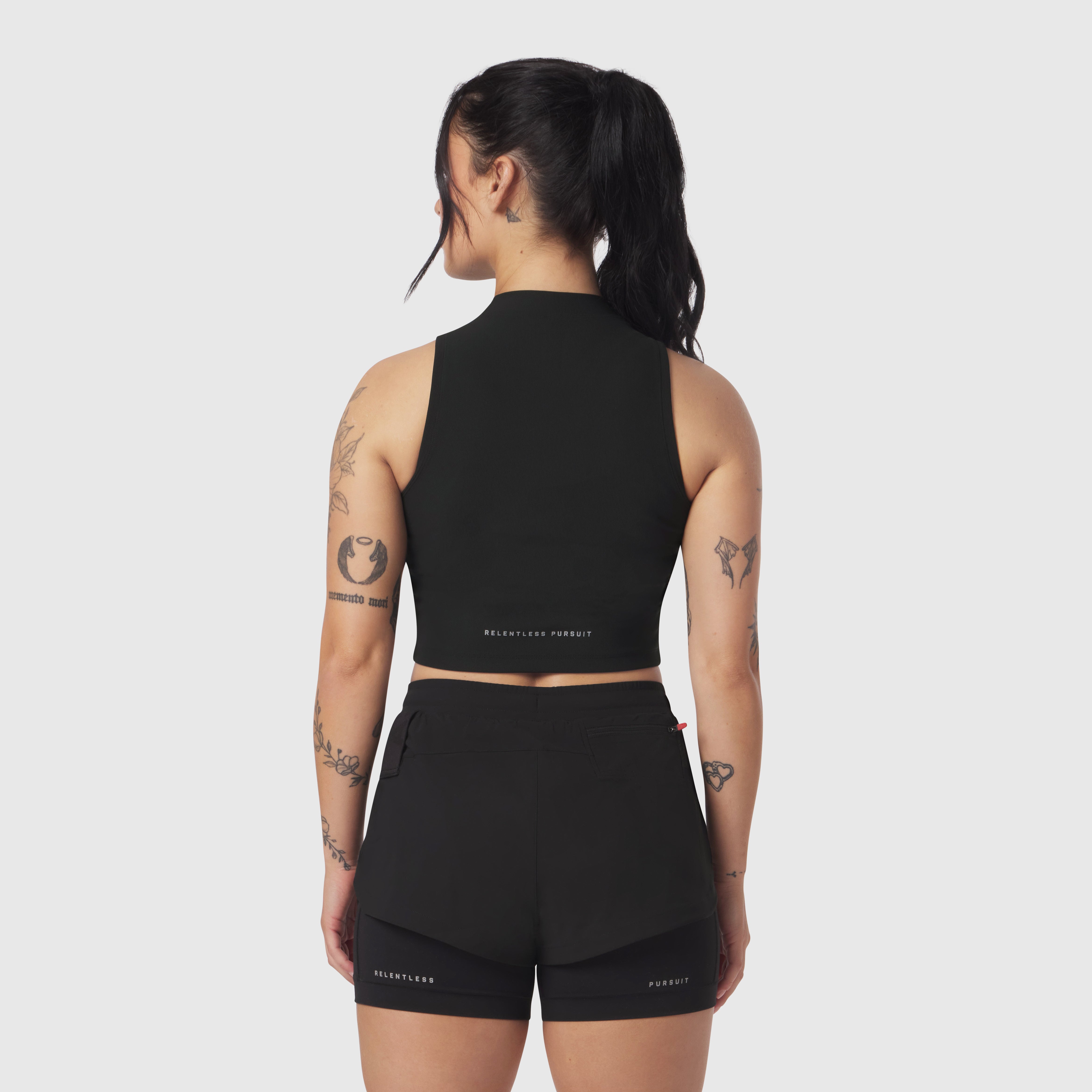 Black Lycra ribbed mockneck tank worn by model, back view, showing cropped fit and midriff