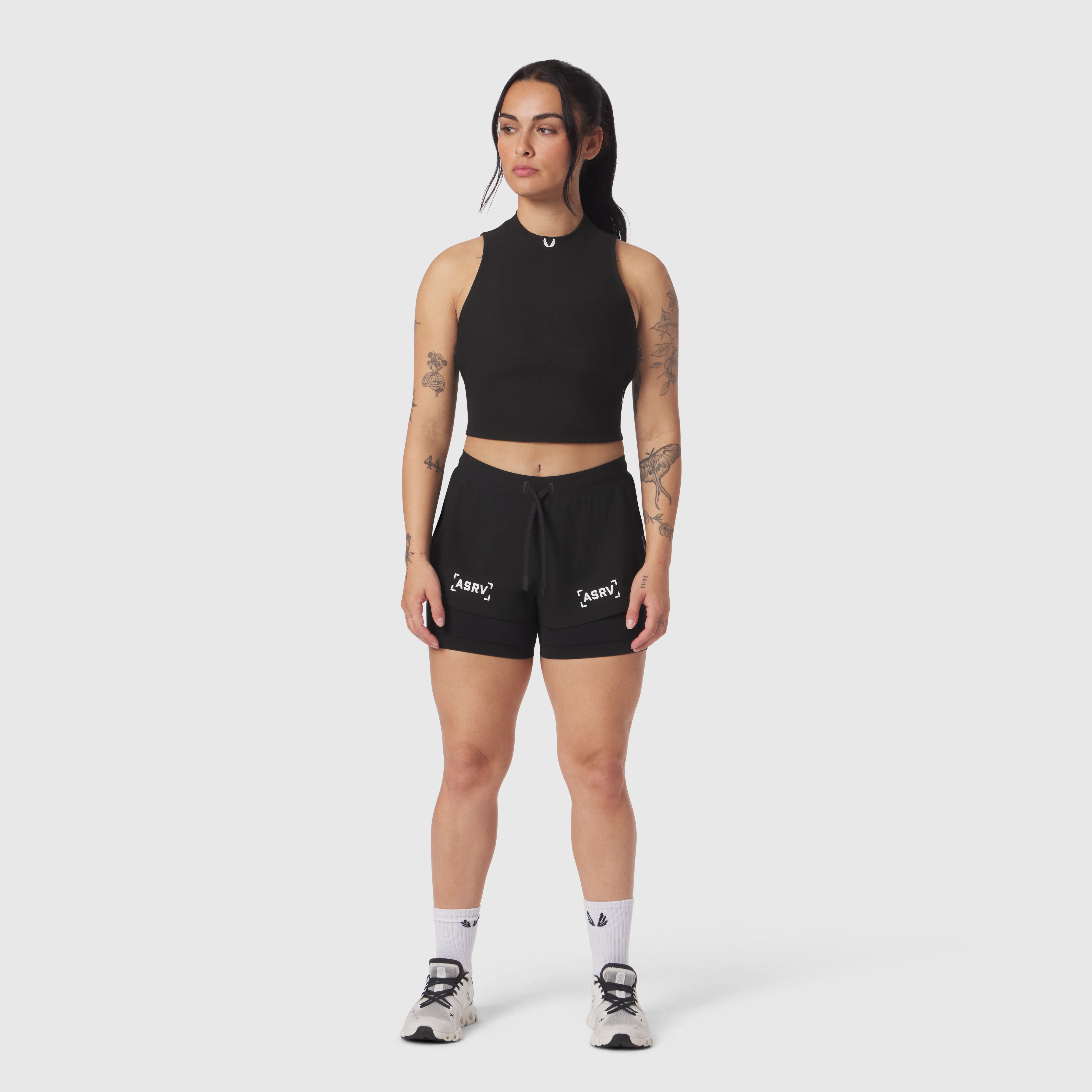 Black ribbed mockneck tank on model, paired with black shorts, front view