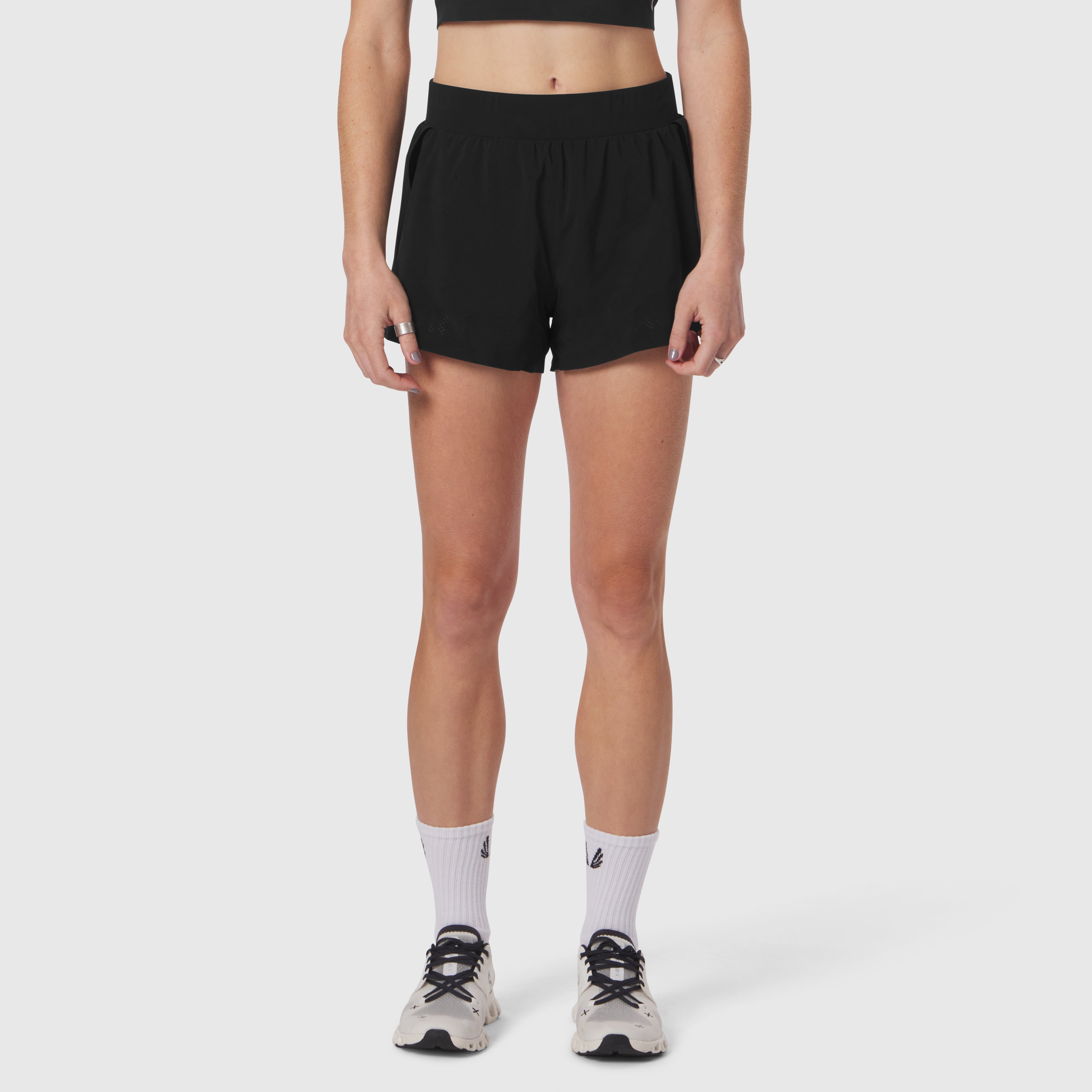 Aerotex Side Split Run Short in black, worn by model with white socks and athletic shoes, front view