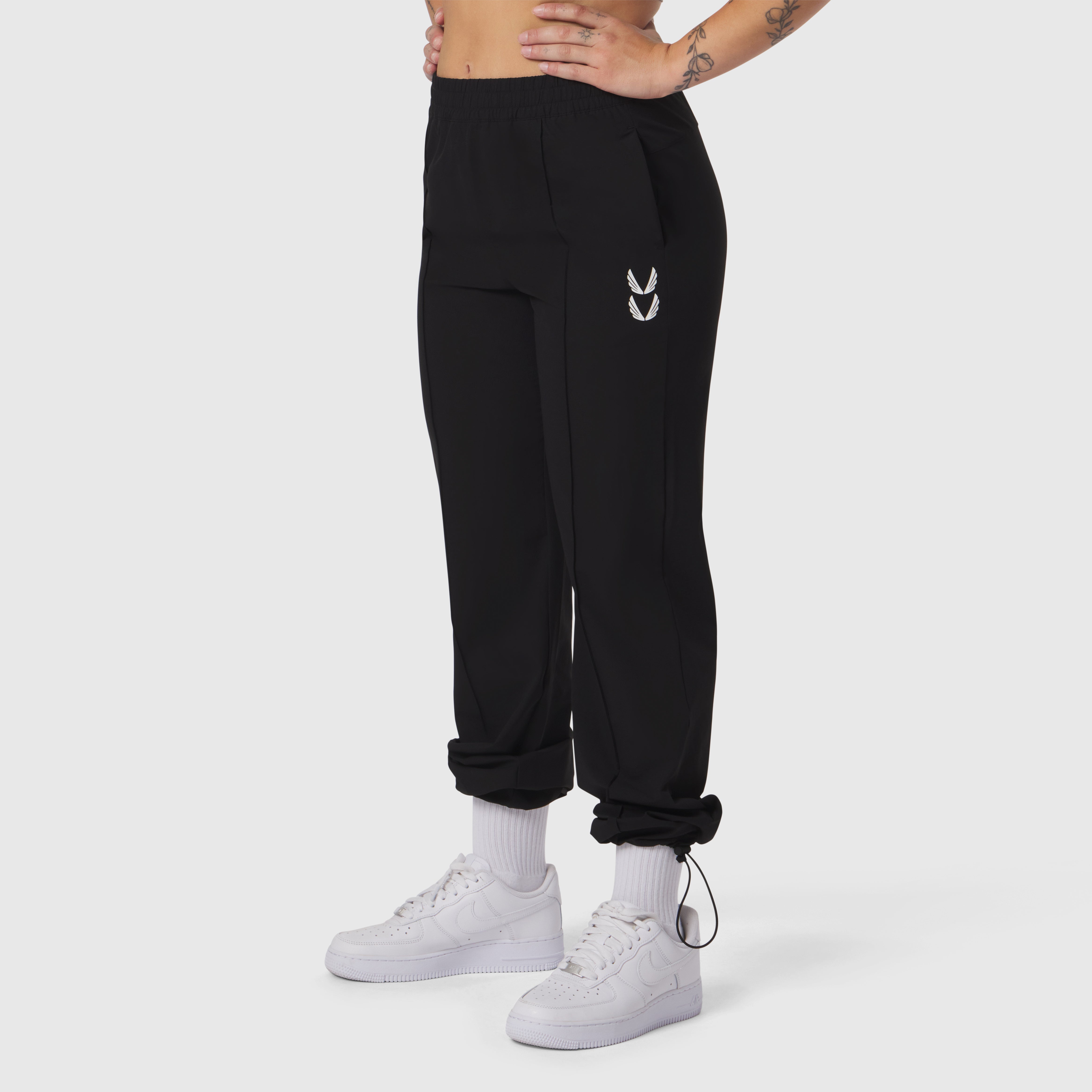 Black ripstop relaxed track pant worn with white sneakers and socks, side view