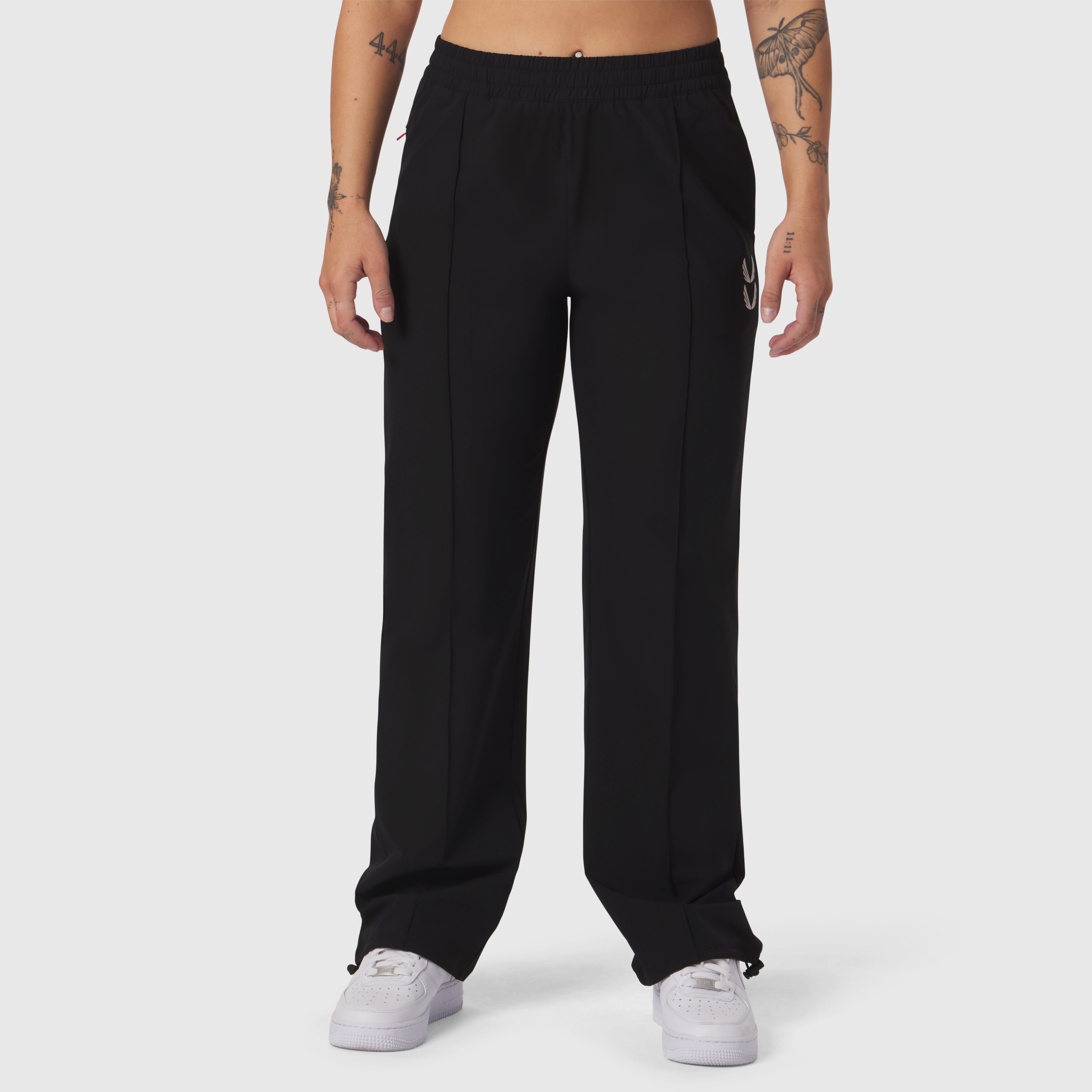 Black ripstop relaxed track pant worn by model with white sneakers, front view