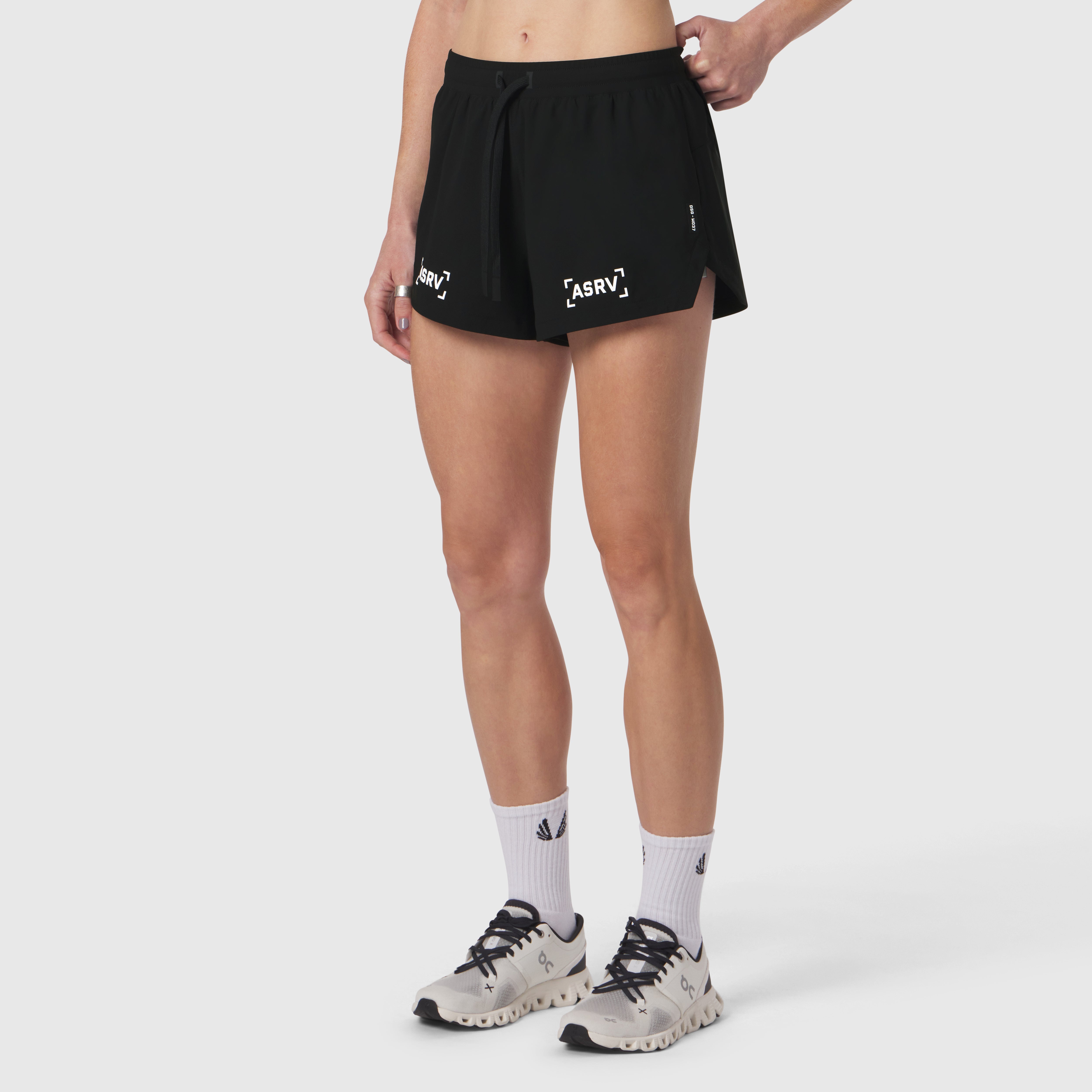 W037 Tetra-Lite Linerless Short in black with bracket design, worn with white socks and beige sneakers