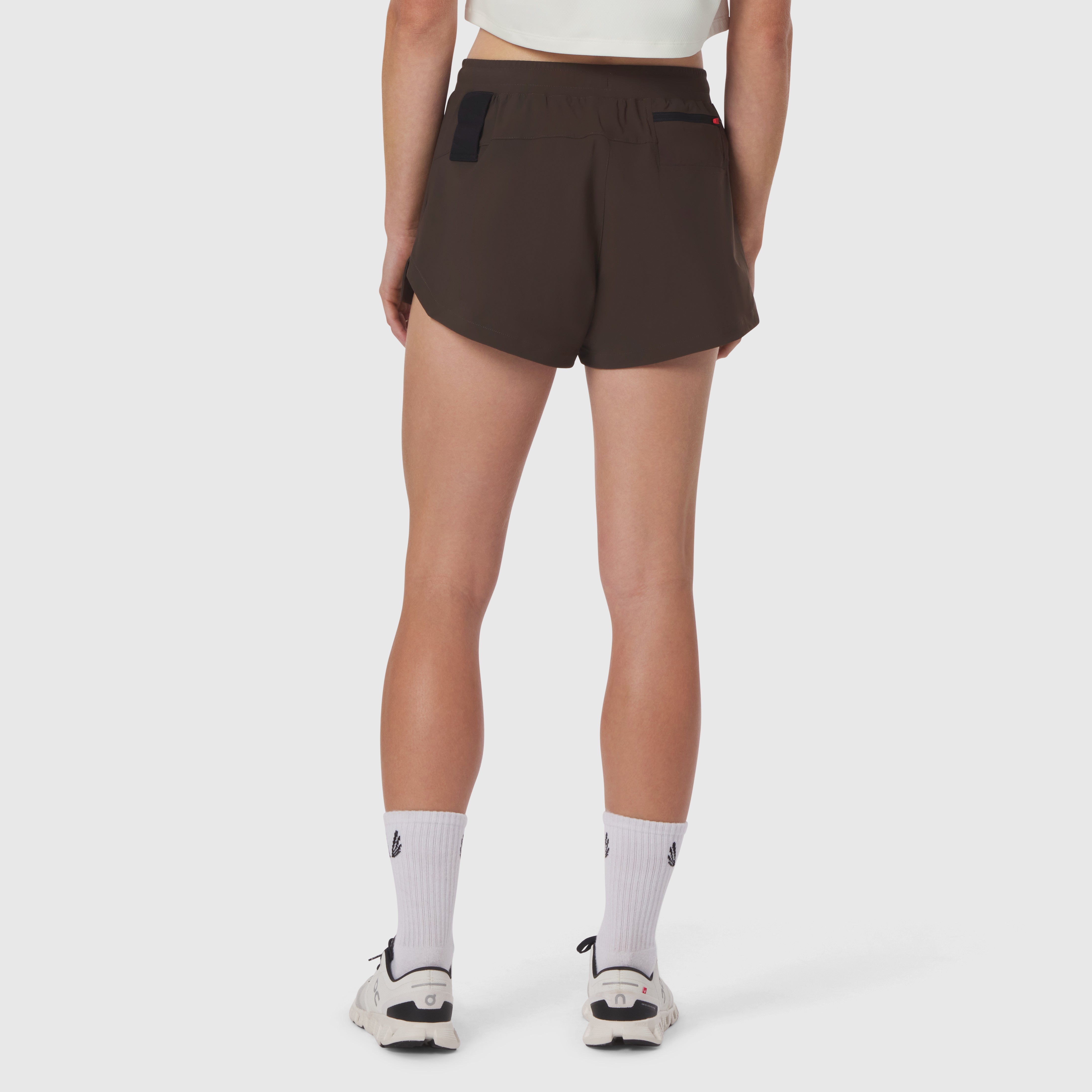 Tetra-Lite Linerless Short in dark earth, back view on model with white socks and sneakers