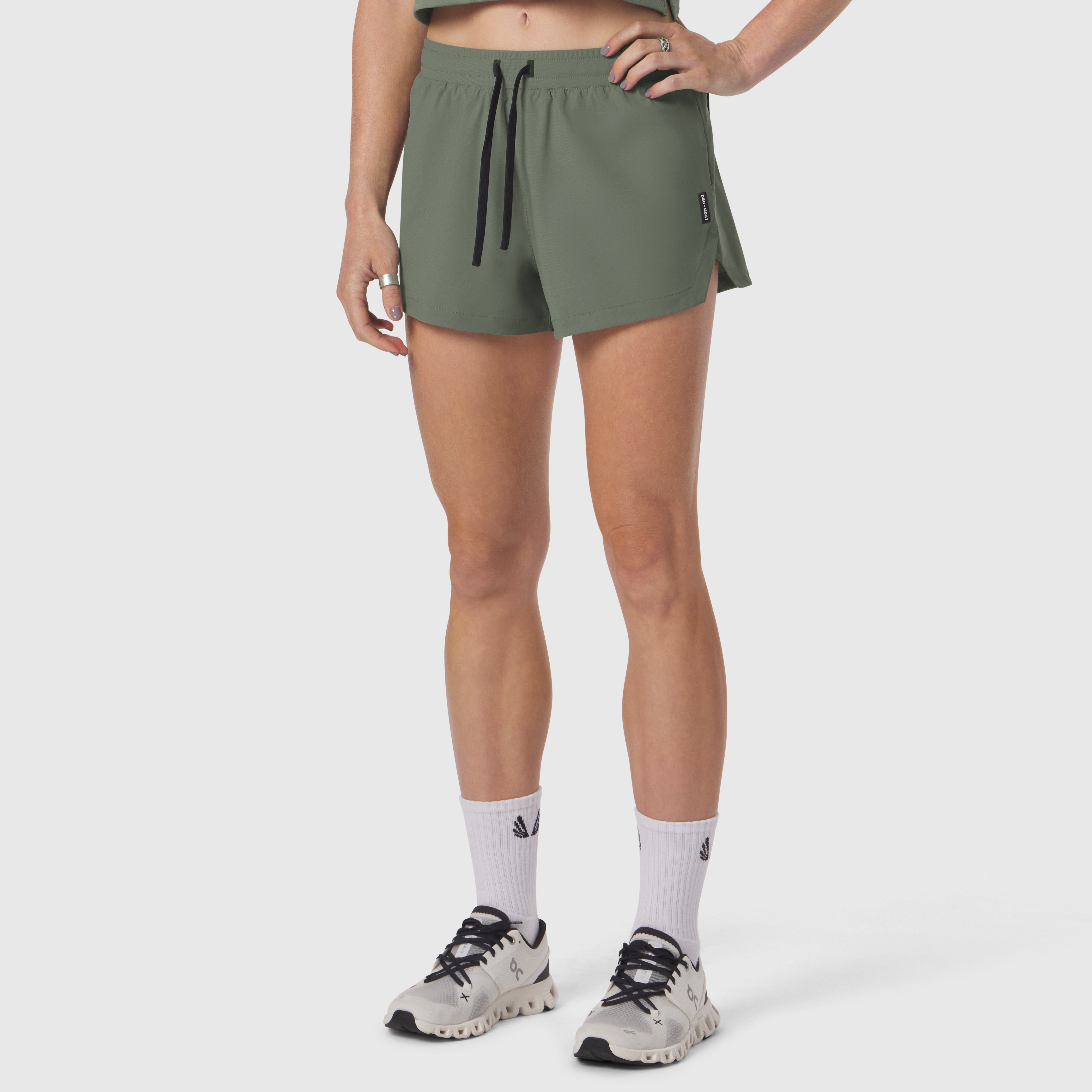 Tetra-Lite Linerless Short in sage, worn with white socks and sneakers, front view
