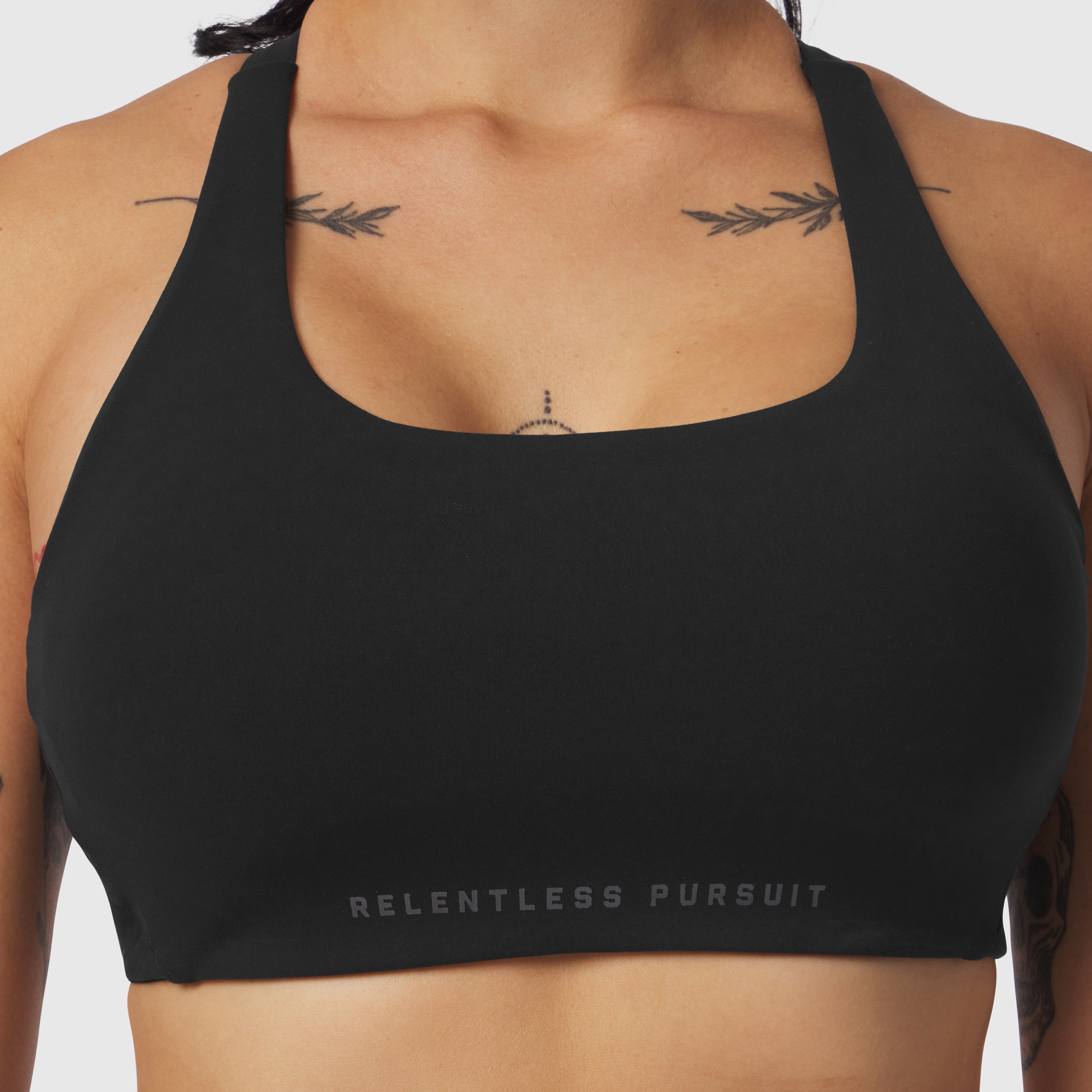 Black LYCRA® Hybrid Sports Bra worn by model, front view showing chest placement and 'Relentless Pursuit' text