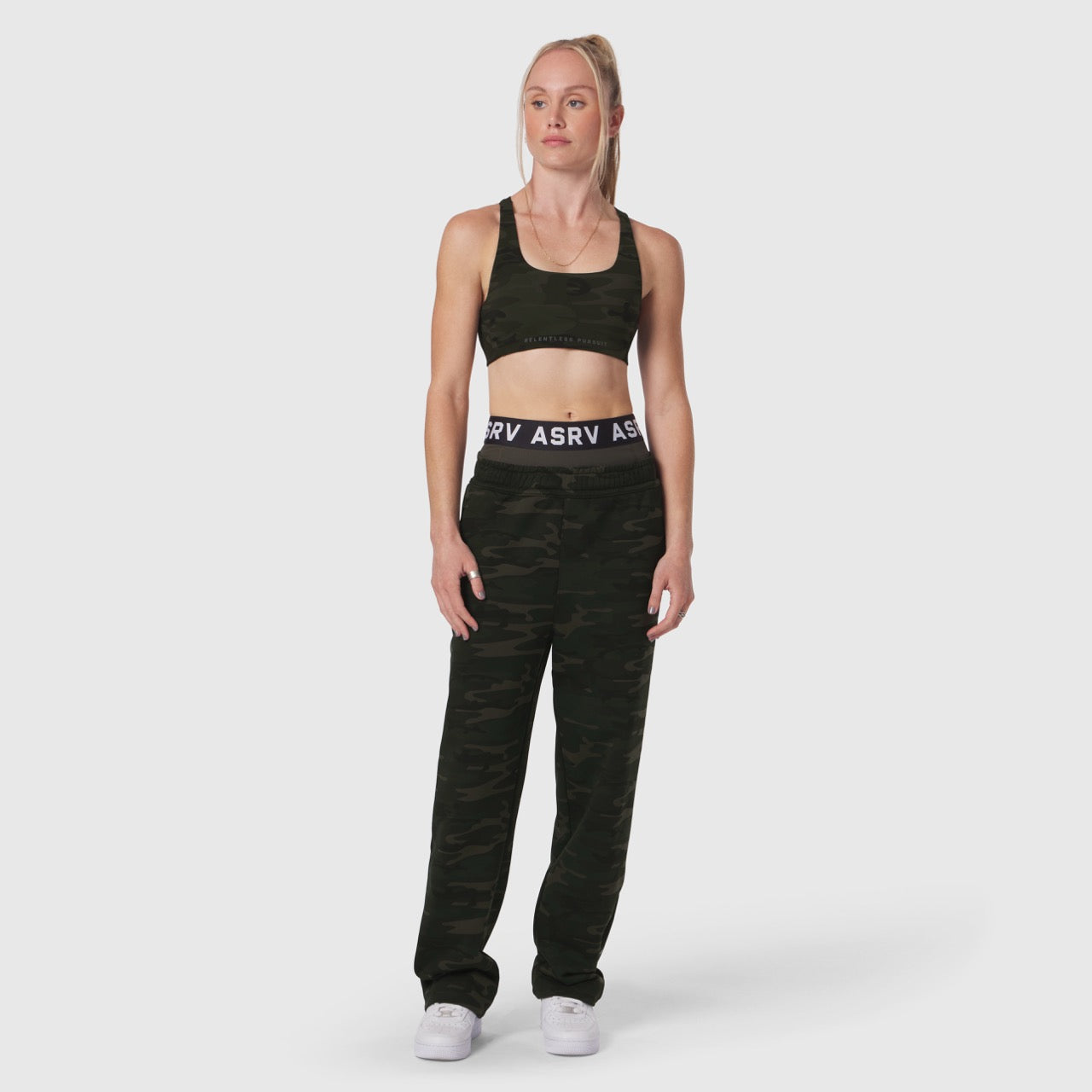 LYCRA® Hybrid Sports Bra in dark camo, worn by model with matching camo joggers, front view