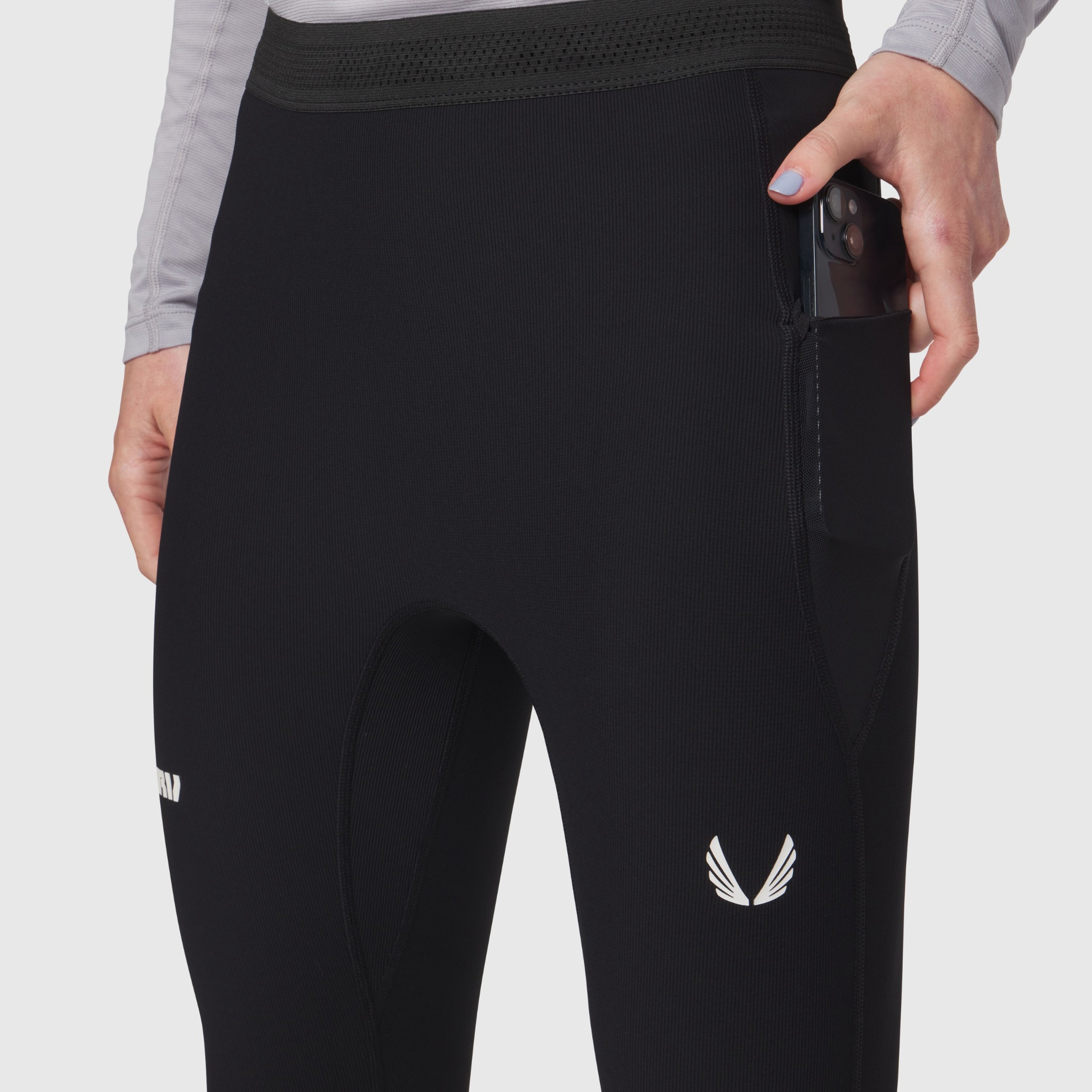 Black Lycra ribbed running tight worn by model, side view showing winged logo detail and side pocket