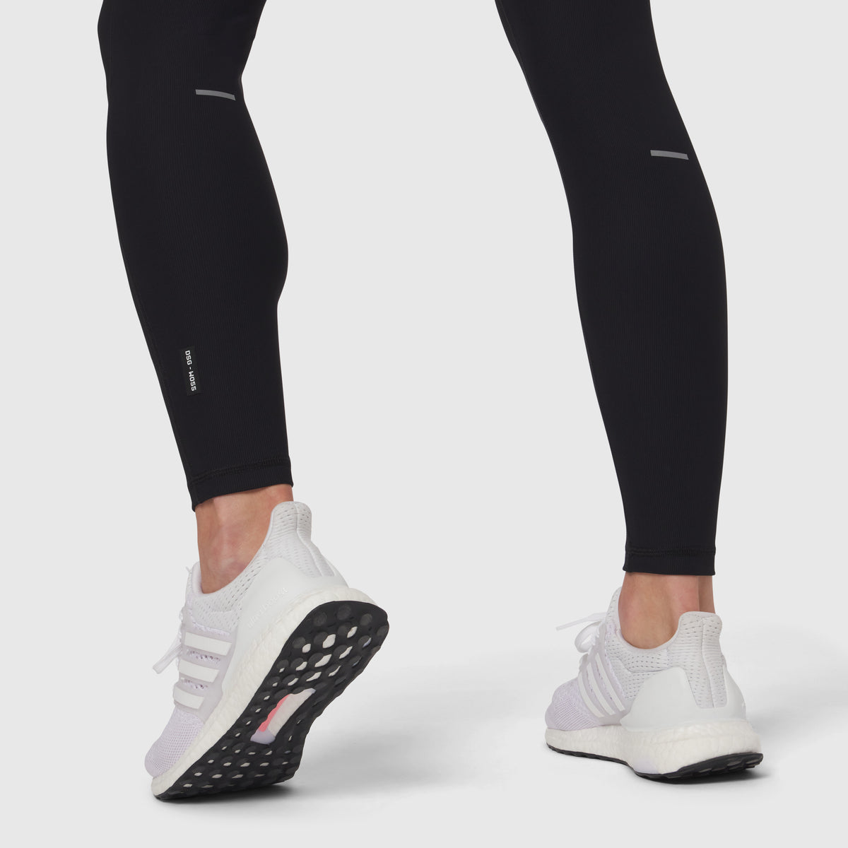 Black Lycra ribbed running tight worn with white sneakers, lower body view