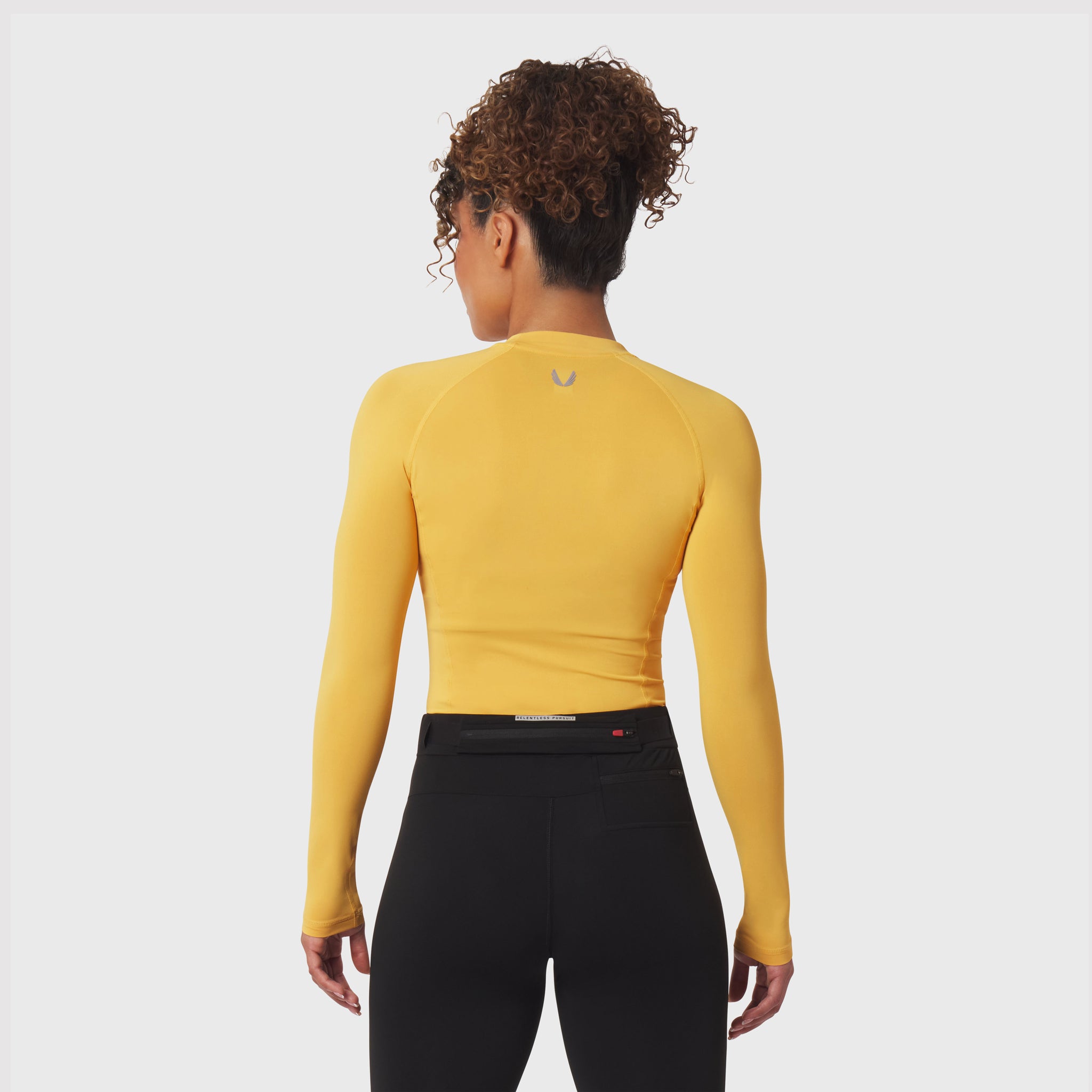 LYCRA® ADAPTIV Baselayer Longsleeve in amber yellow, worn by model, back view