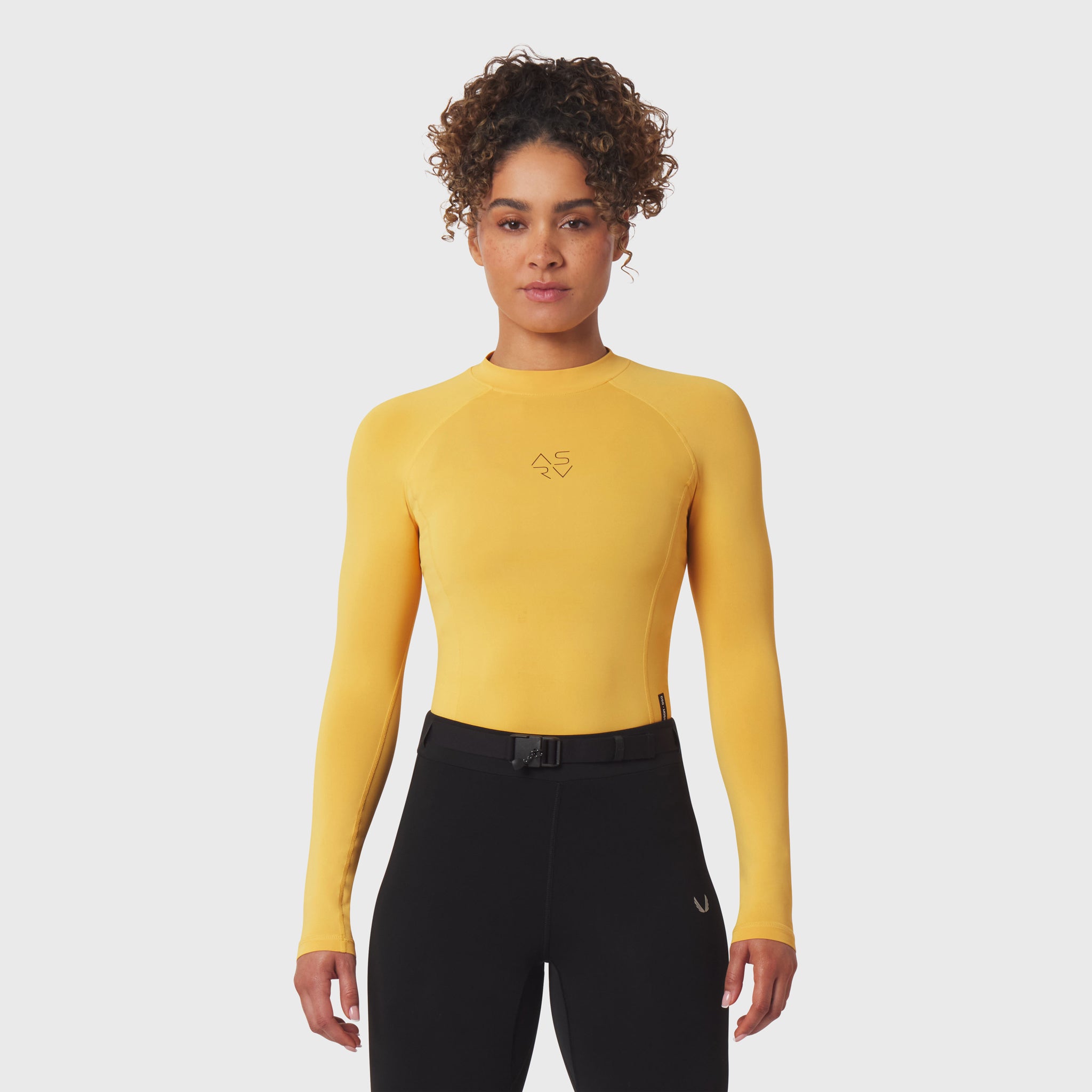 LYCRA® ADAPTIV Baselayer Longsleeve in amber yellow, worn with black shorts, front view