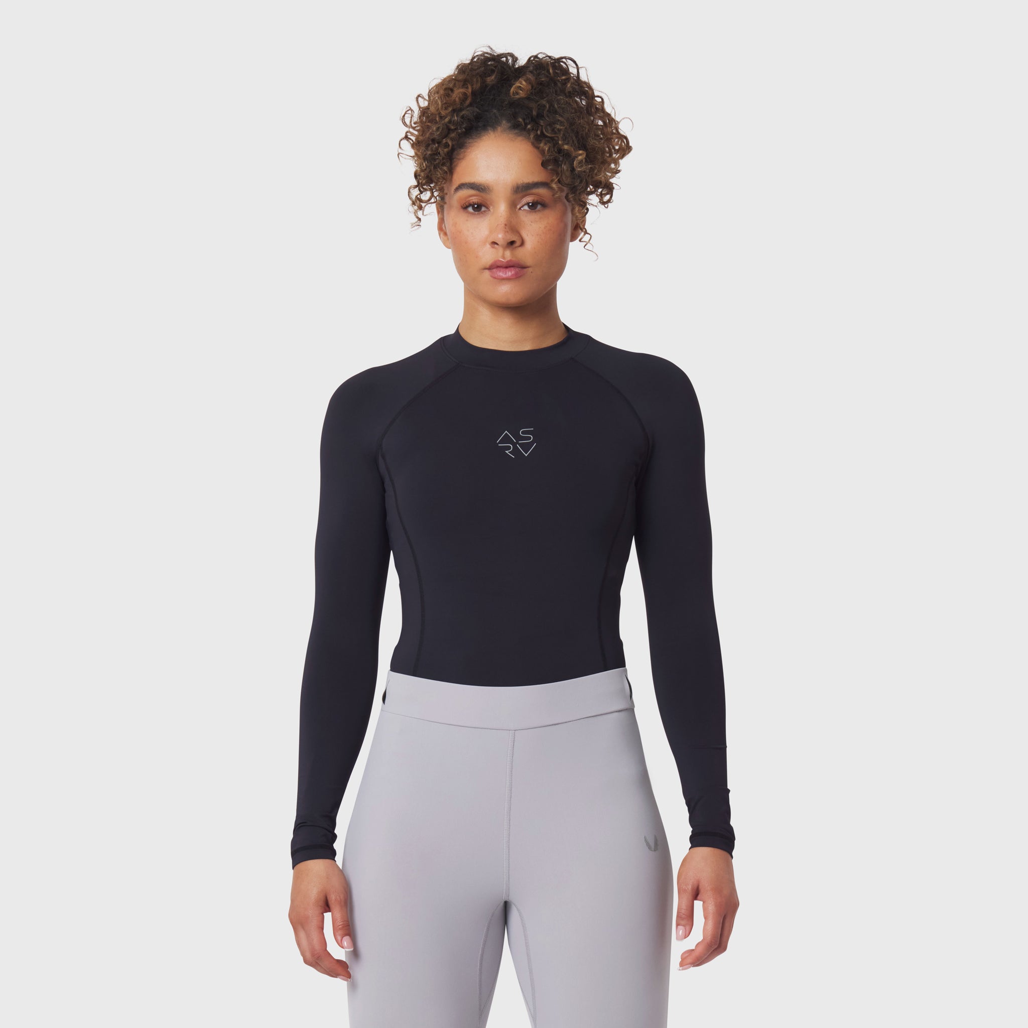 LYCRA® ADAPTIV Baselayer Longsleeve in black, worn with grey leggings, front view