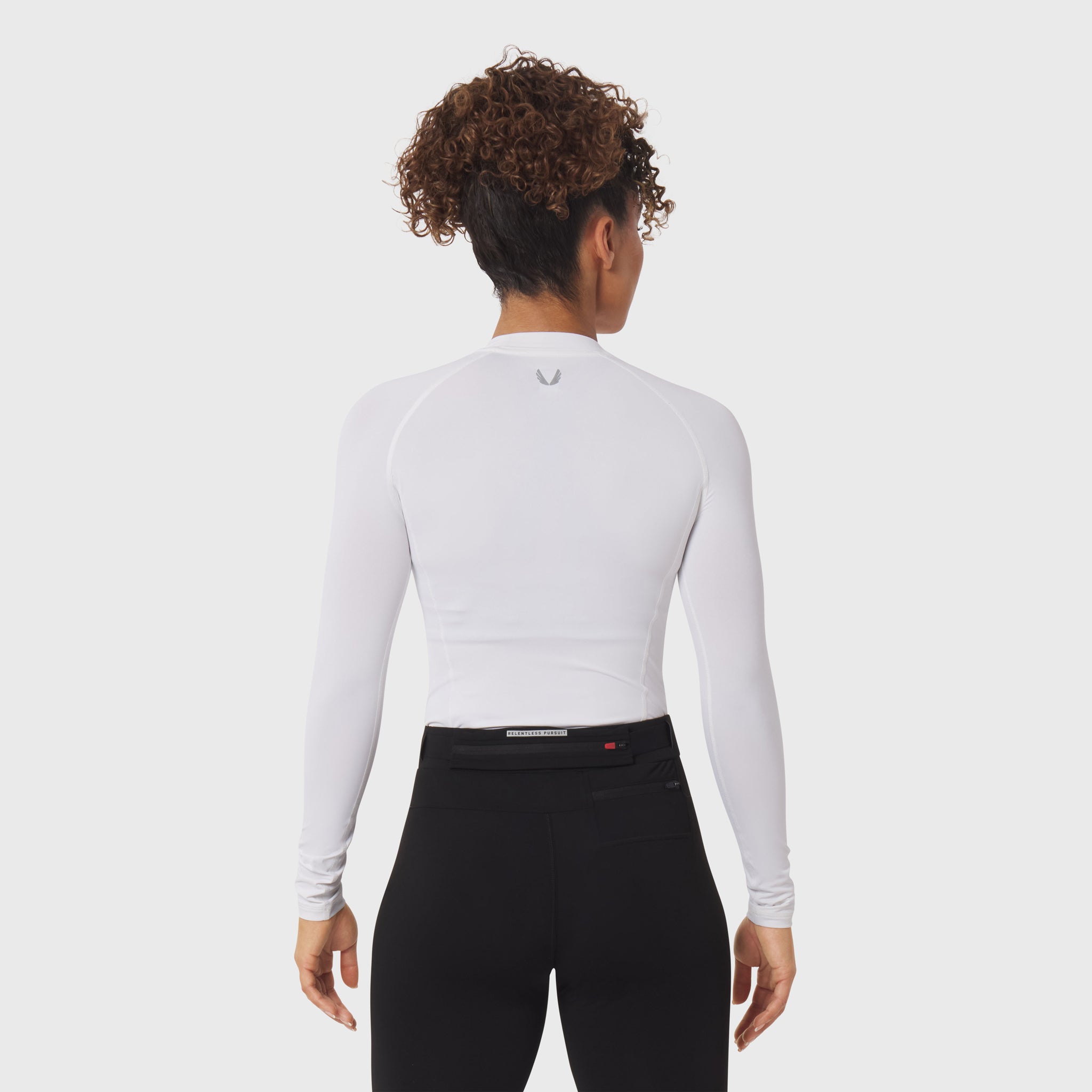 White LYCRA® ADAPTIV baselayer longsleeve worn with black leggings, back view