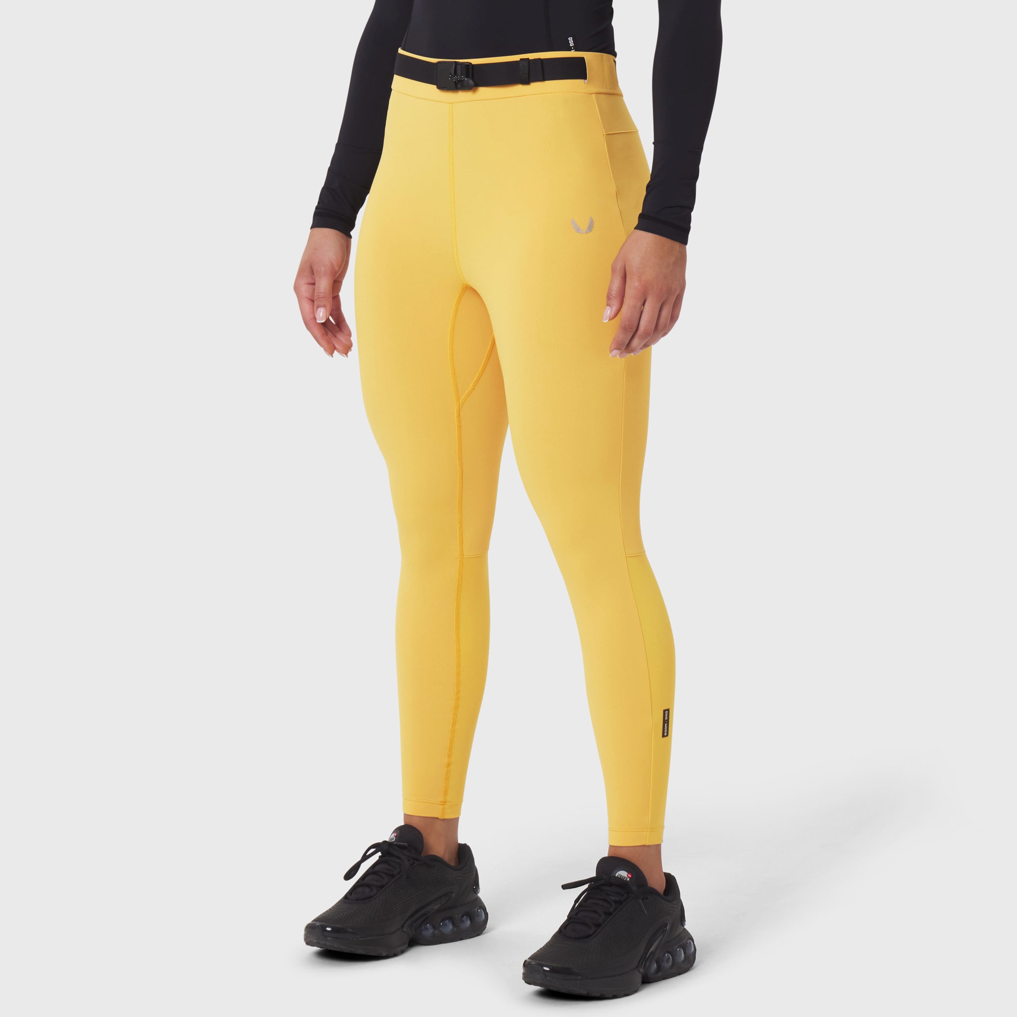 Hybrid Belt-Pack Run Legging in amber yellow worn by model with black long-sleeve top and black sneakers