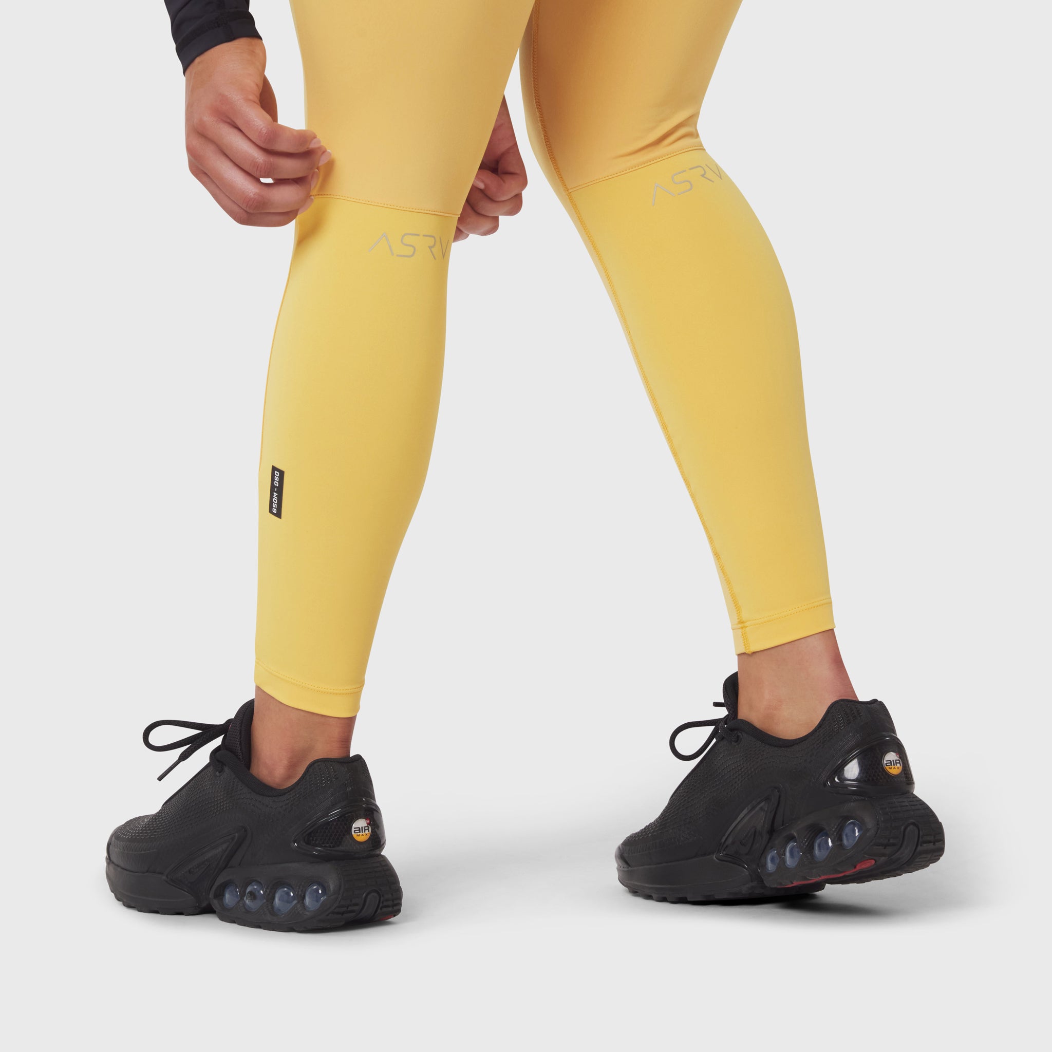 W059 Hybrid Belt-Pack Run Legging in amber yellow worn with black sneakers, lower body view