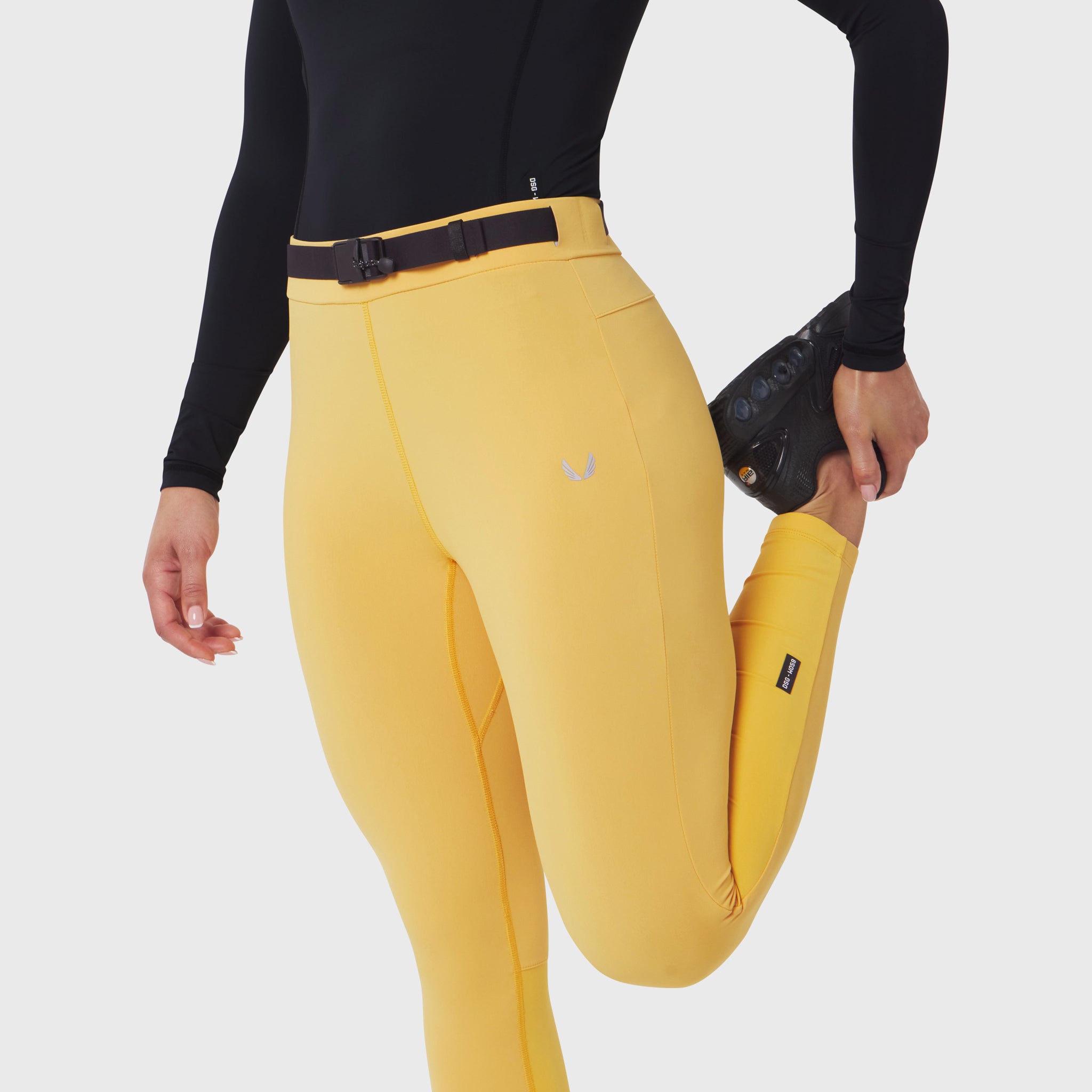 W059 Hybrid Belt-Pack Run Legging in amber yellow, worn by model with black long-sleeve top and black gloves