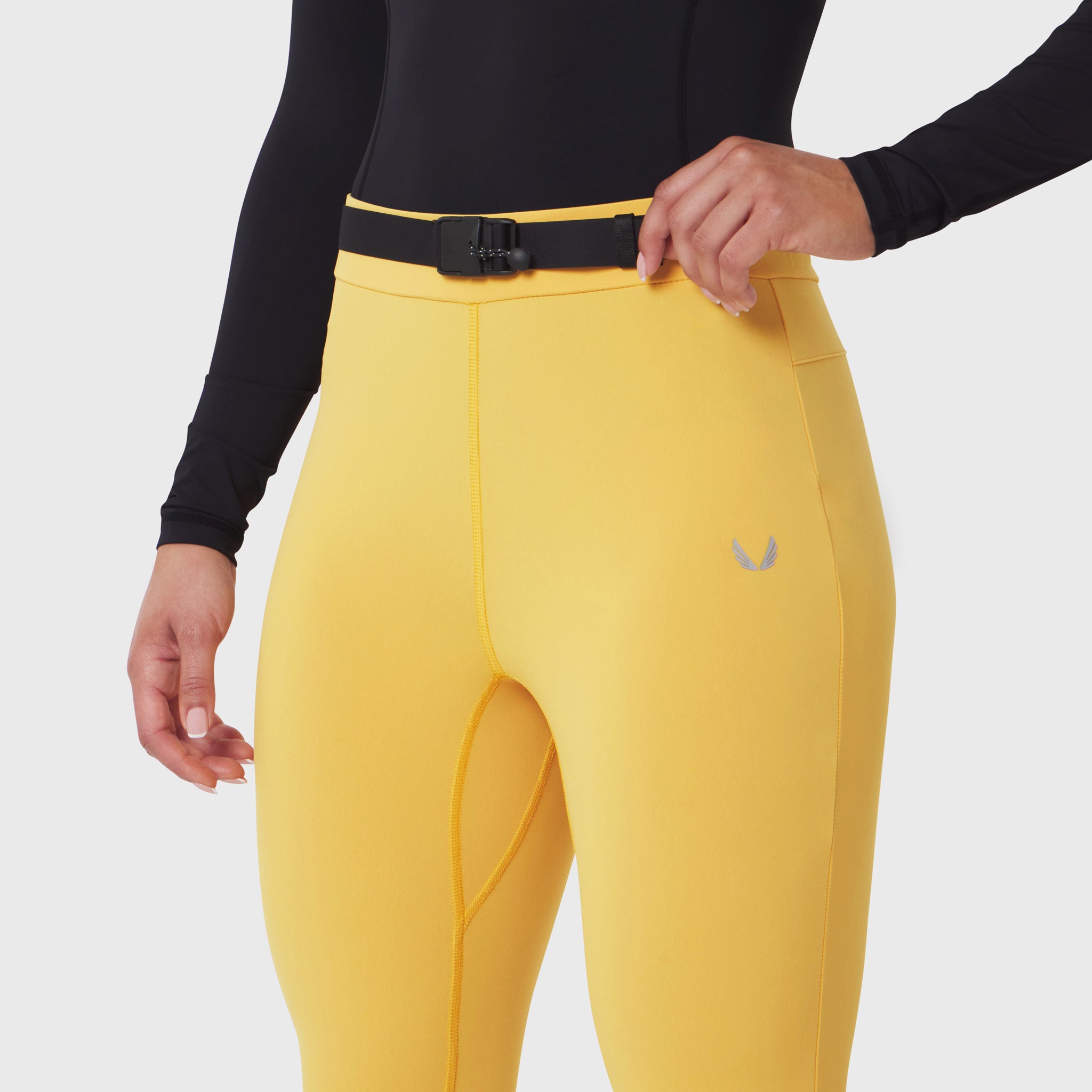 W059 Hybrid Belt-Pack Run Legging in amber, worn with black long-sleeve top and black belt
