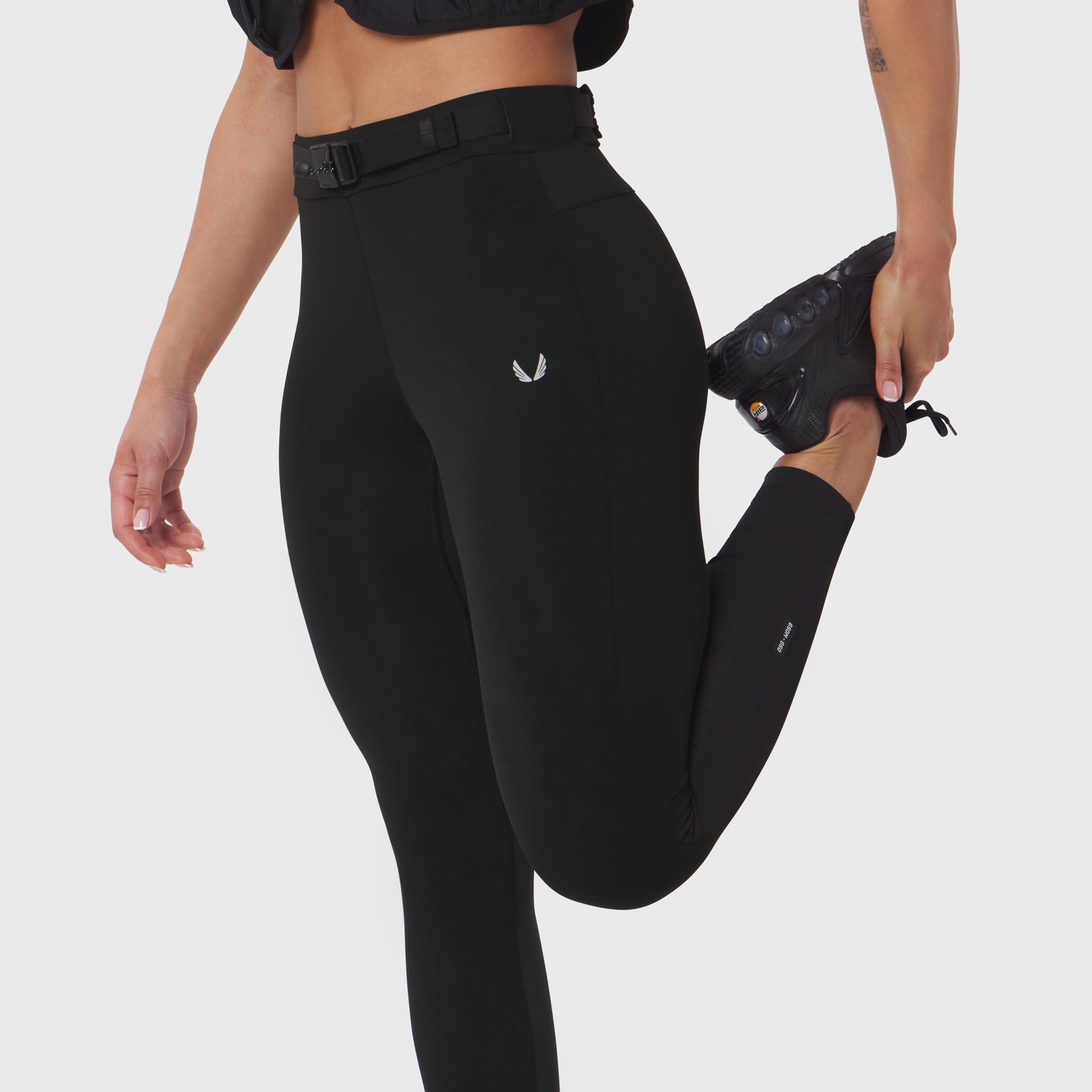 Black hybrid belt-pack run legging worn by model in standing pose with leg raised