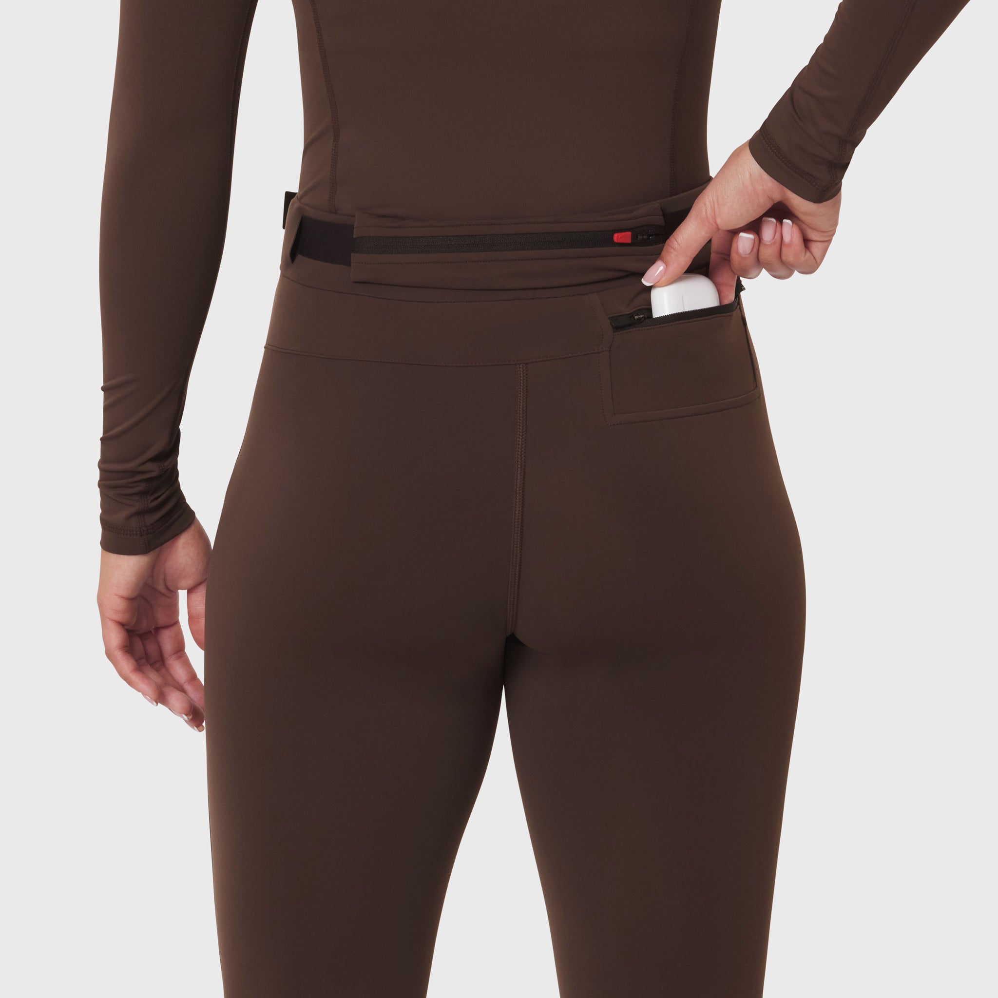 W059 Hybrid Belt-Pack Run Legging in Dark Earth, model wearing and demonstrating belt-pack pocket