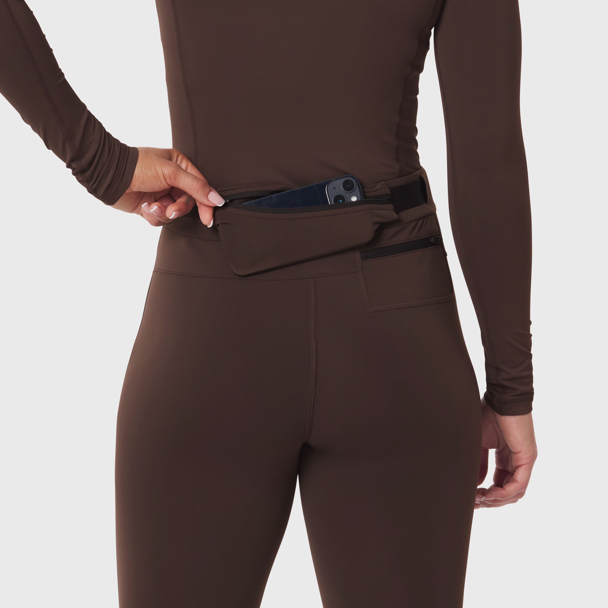W059 Hybrid Belt-Pack Run Legging in dark earth, worn by model showing waistband pocket detail