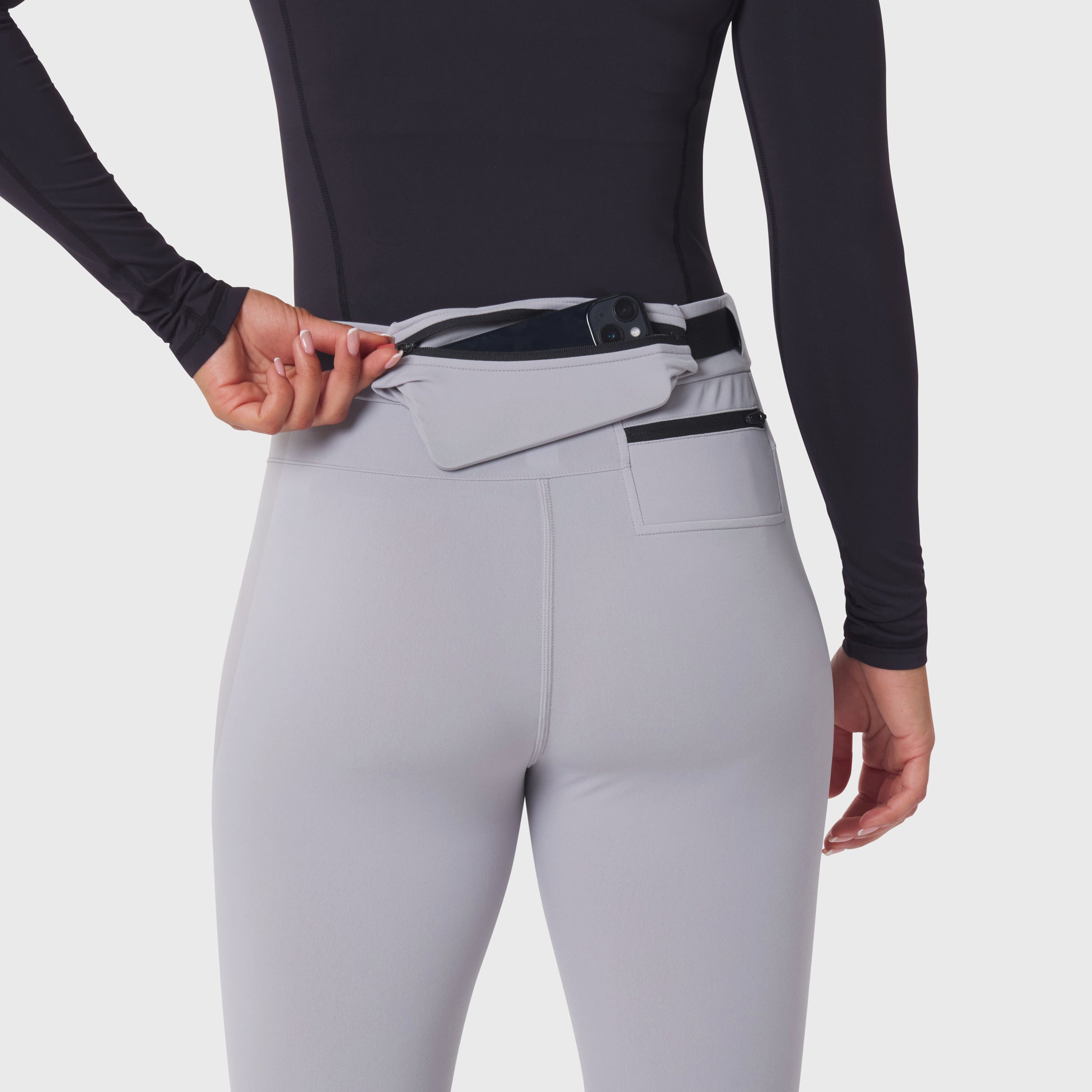 W059 Hybrid Belt-Pack Run Legging in slate grey, worn with model adjusting belt pack at waist