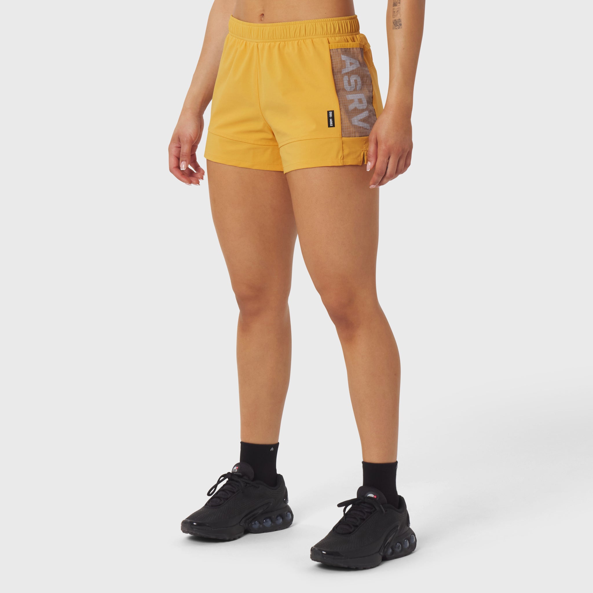 Tetra-Lite Adventure Short in amber yellow with contrasting side pocket, modeled with black sneakers