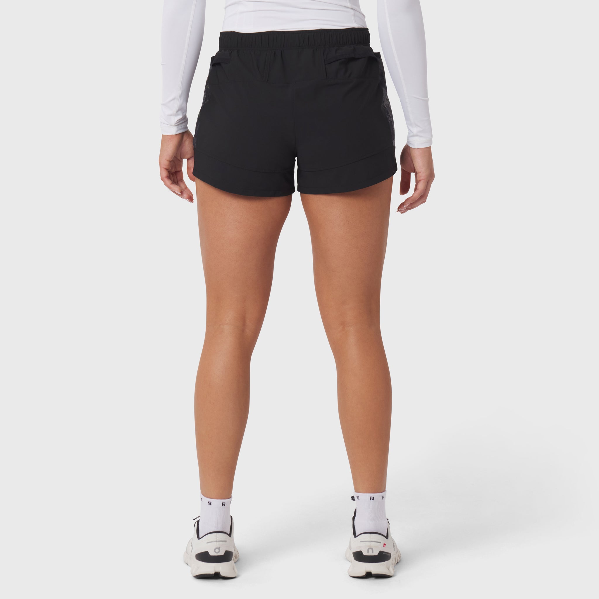 Black Tetra-Lite Adventure Short worn by model with white long-sleeve top and white sneakers, front view