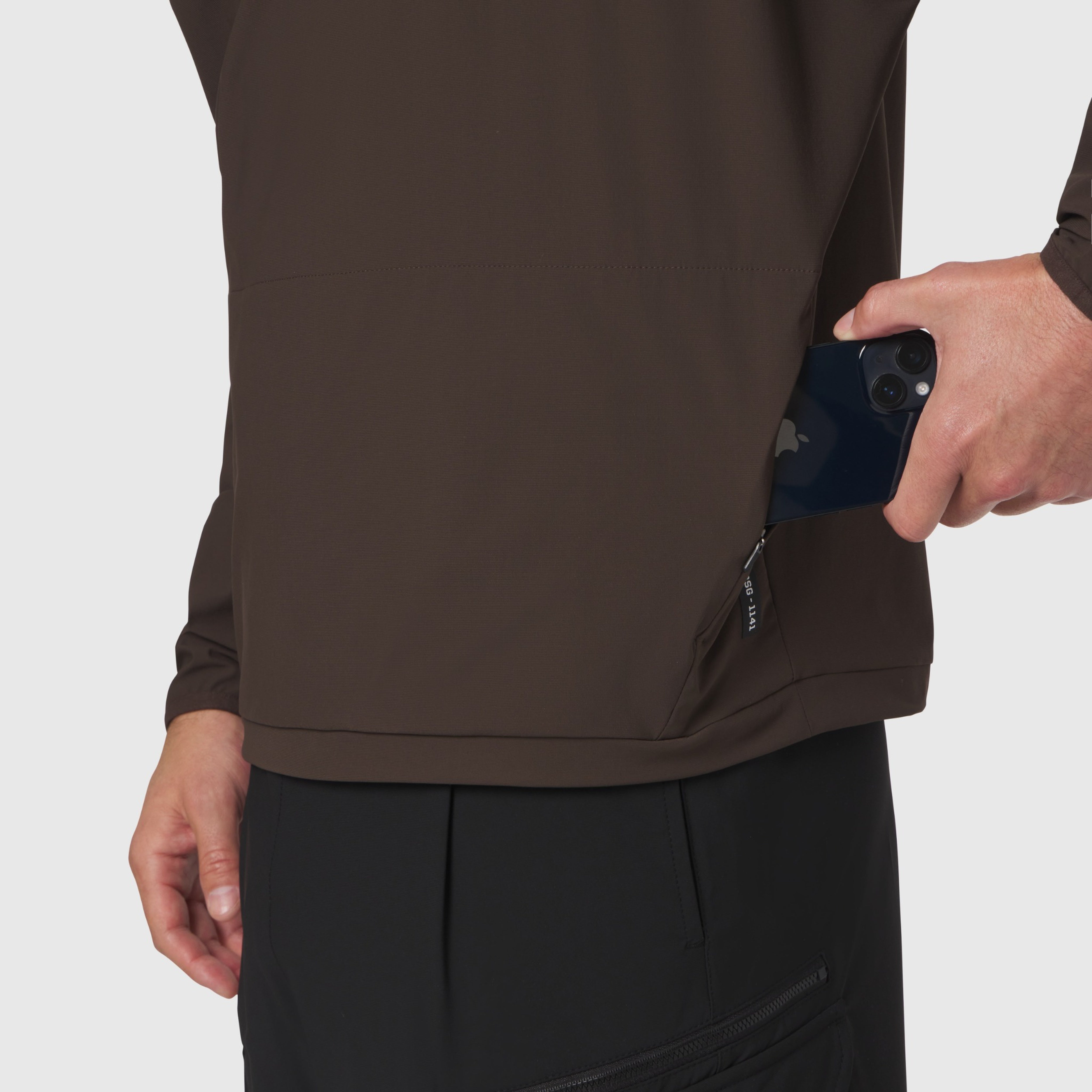 Tetra-Lite Blade Collar Zip Jacket in dark earth worn by model holding phone, side view