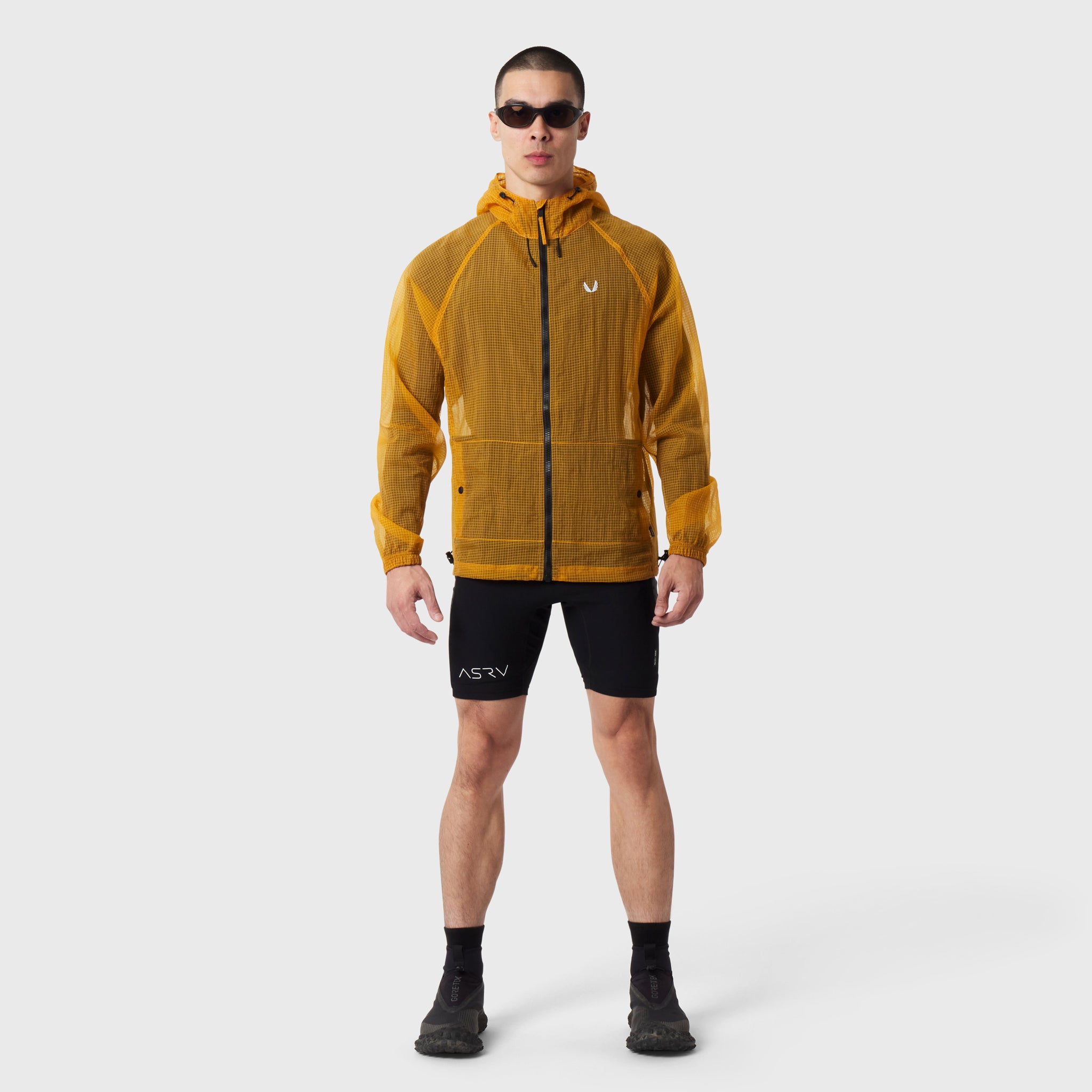 Weather-Ready Transparent Ripstop Shell Jacket in amber, worn by model with black shorts, front view