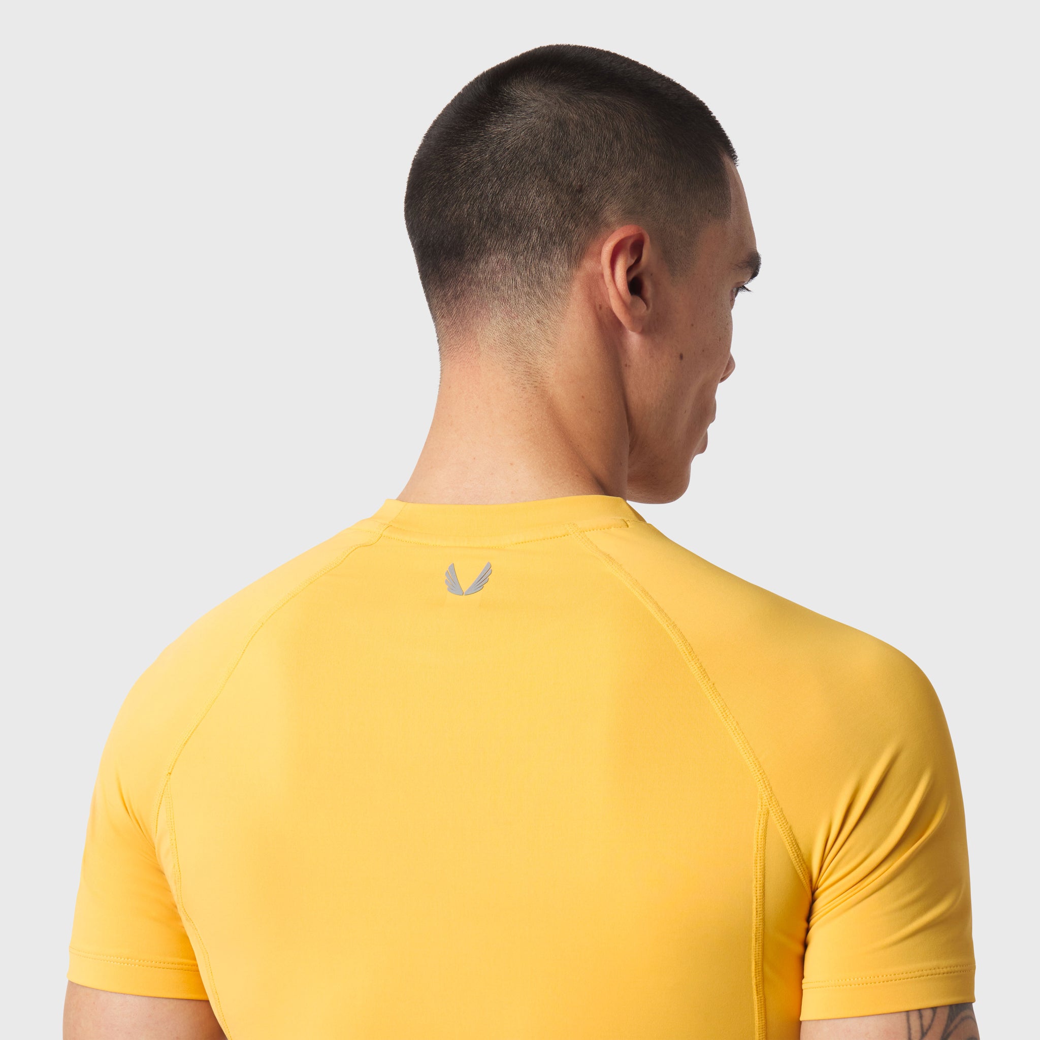LYCRA® ADAPTIV Baselayer Shortsleeve in amber yellow, back view on model