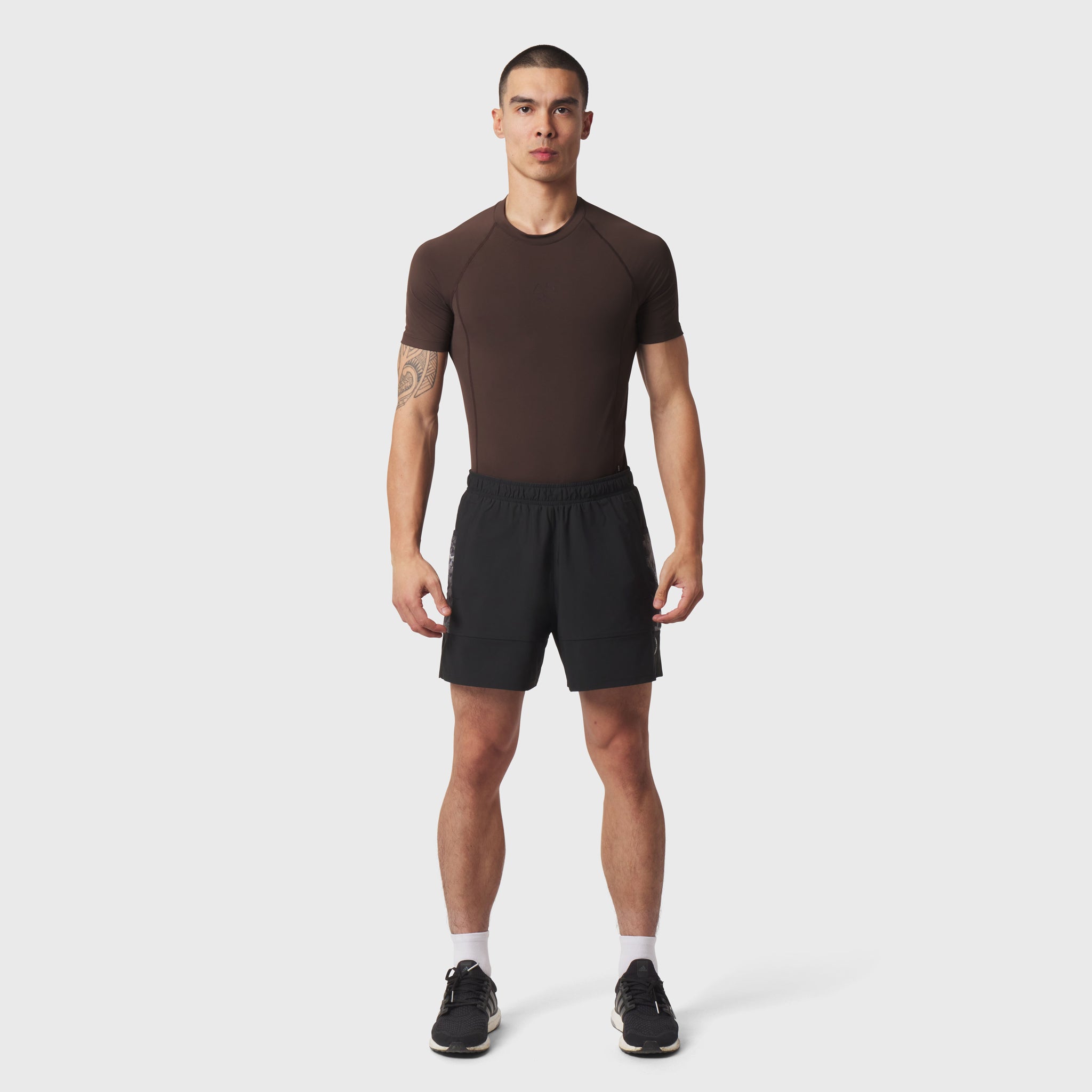 LYCRA® ADAPTIV Baselayer Shortsleeve in dark brown worn with black shorts, front view