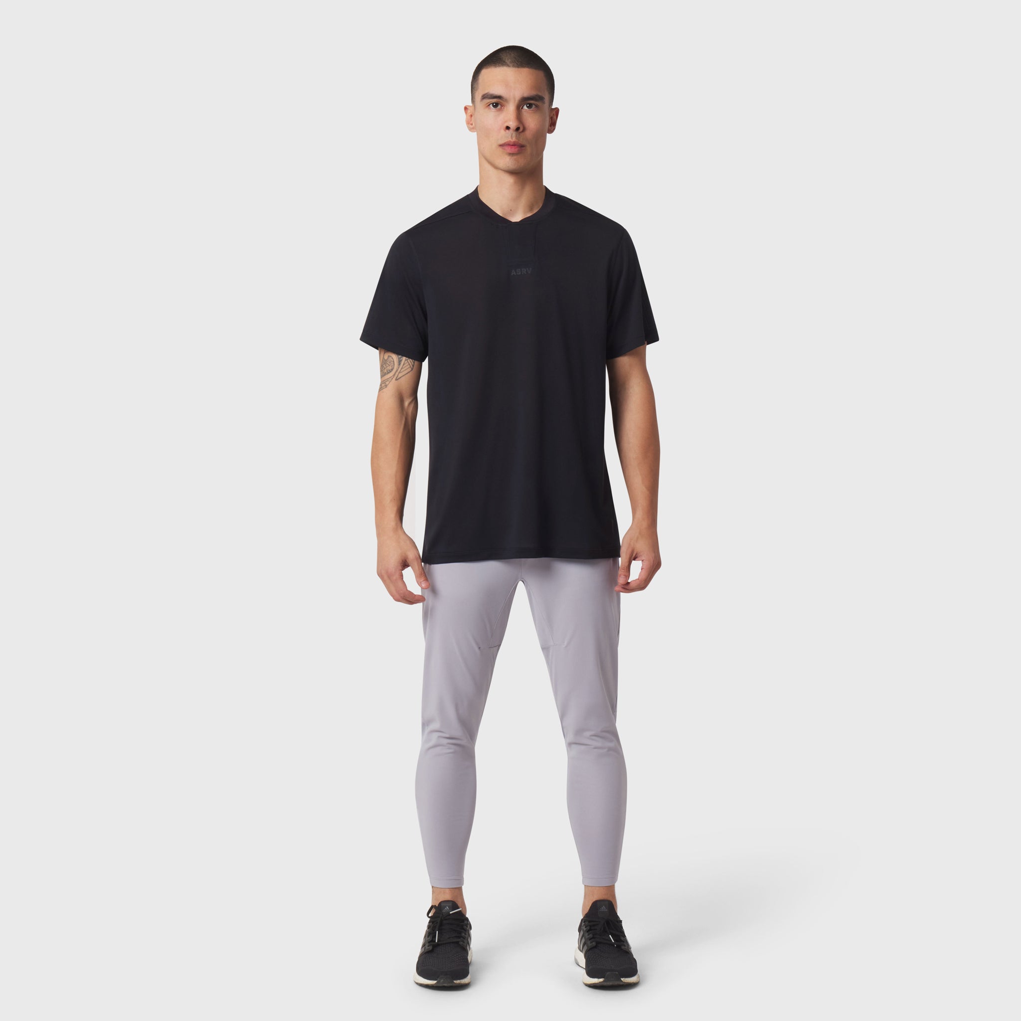 Black v-neck t-shirt with grey leggings and black sneakers, front view on model