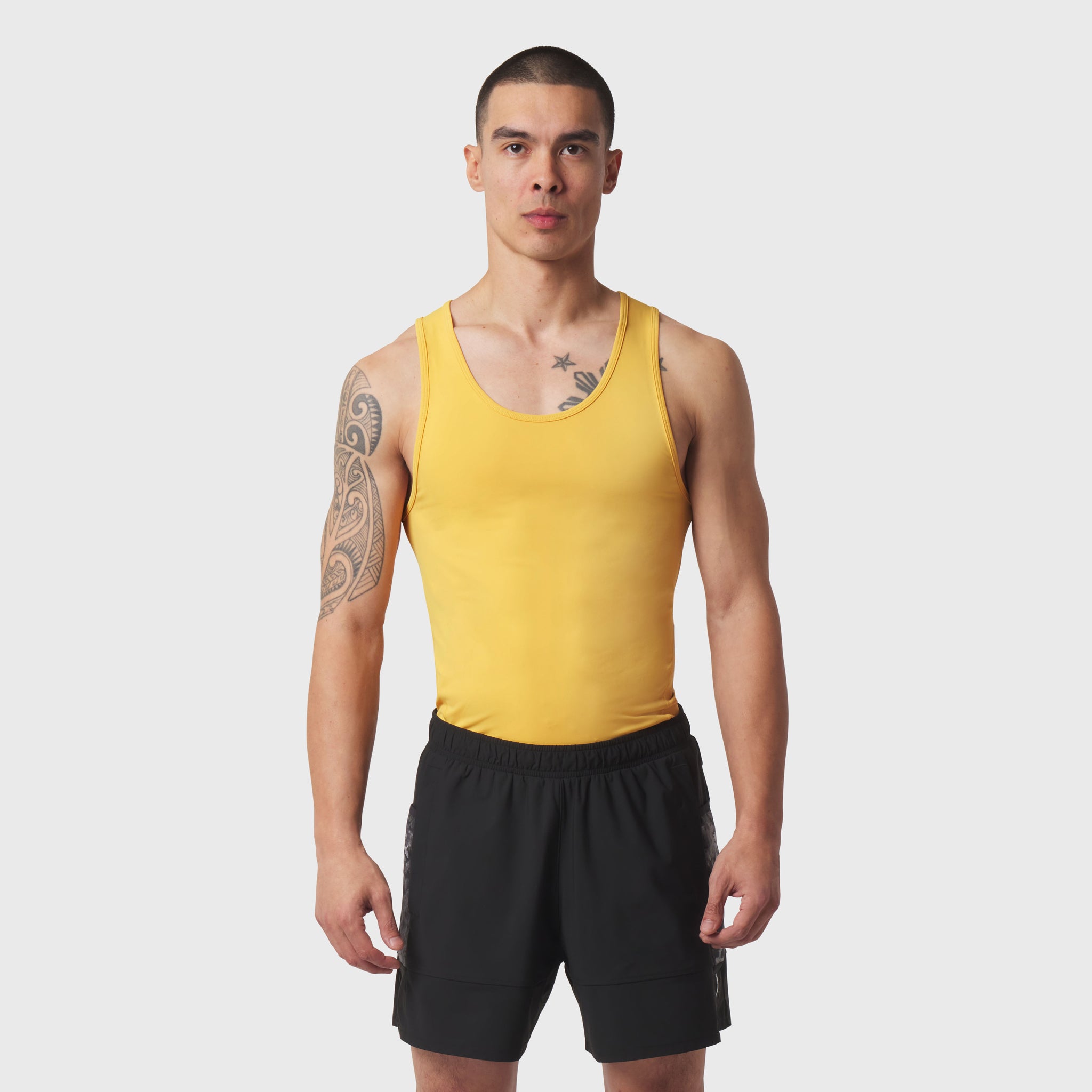 LYCRA® ADAPTIV Baselayer Tank in amber yellow worn with black shorts, front view on model