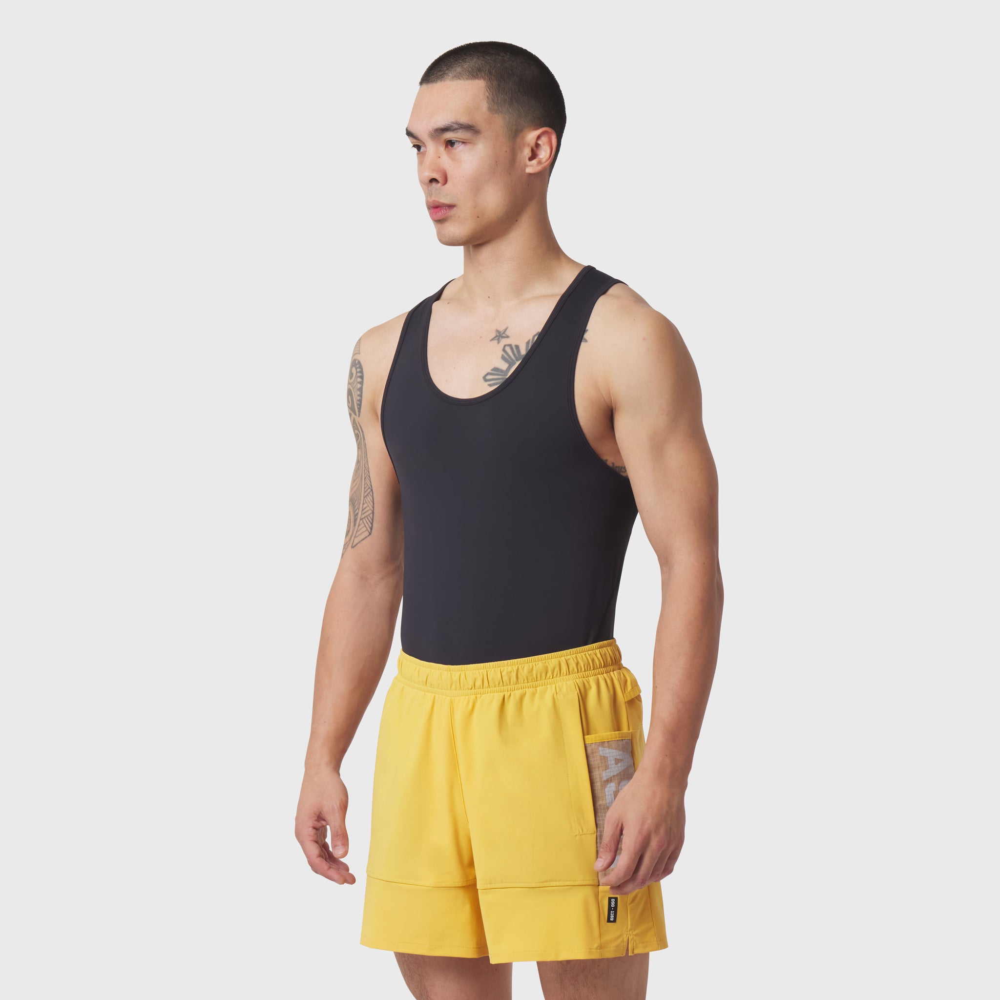 Black LYCRA® ADAPTIV baselayer tank worn with yellow shorts, side view